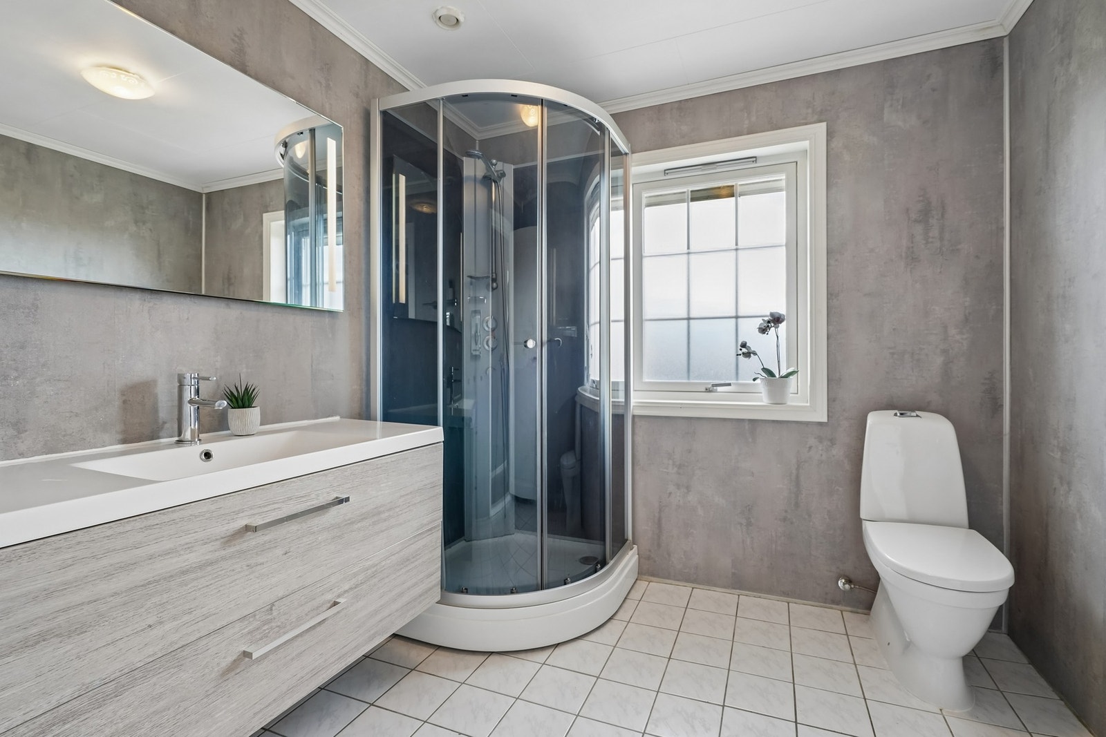 Badet i 1.etasjen har fliset gulv med elektriske varmekabler, og på veggene er det baderomsplater. Galleribilde