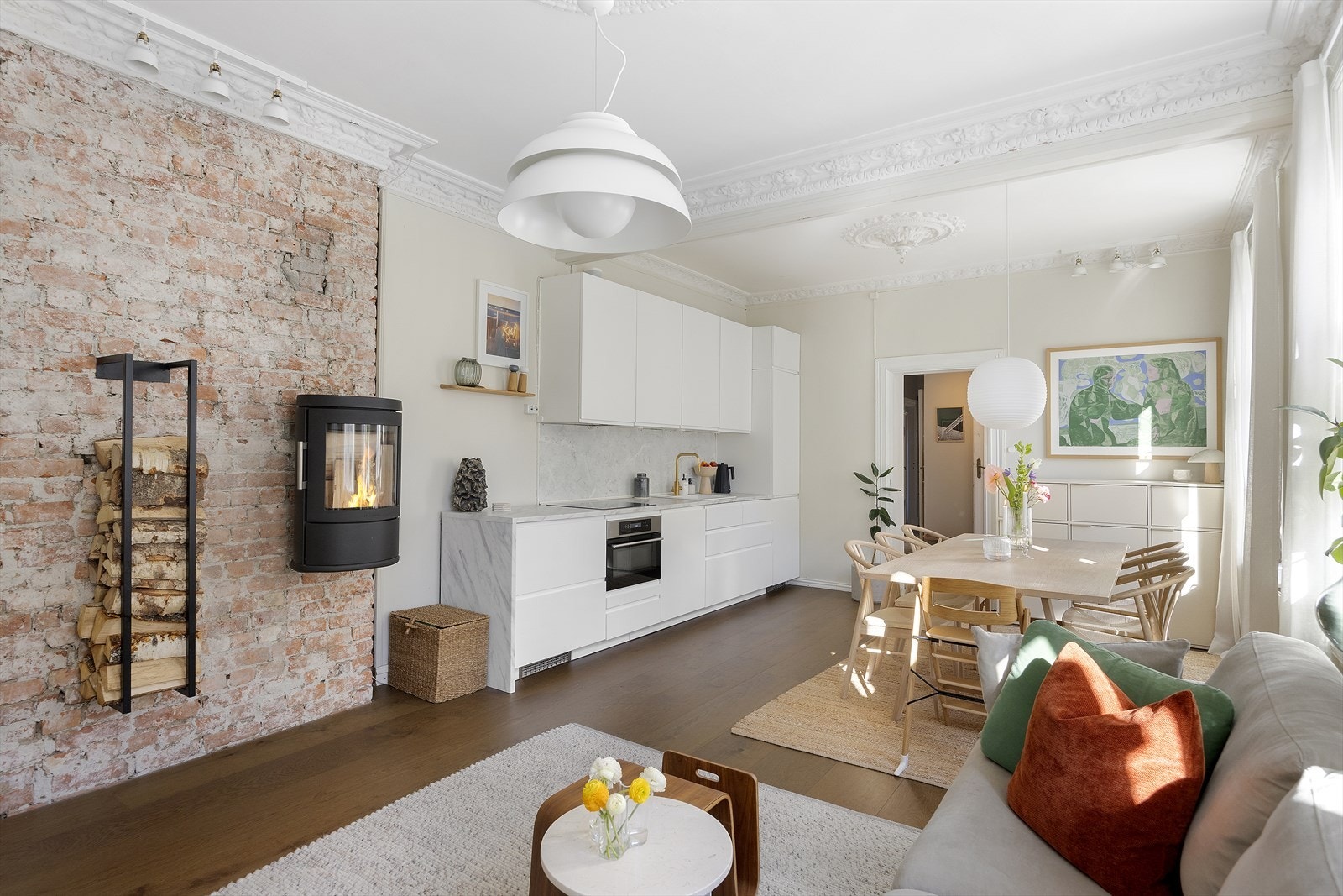 Stuen kombinerer lekre klassiske bygårdsdetaljer med synlig teglvegg og god plass til møblering. Nytt parkettgulv lagt i 2021 i stue/kjøkken Galleribilde