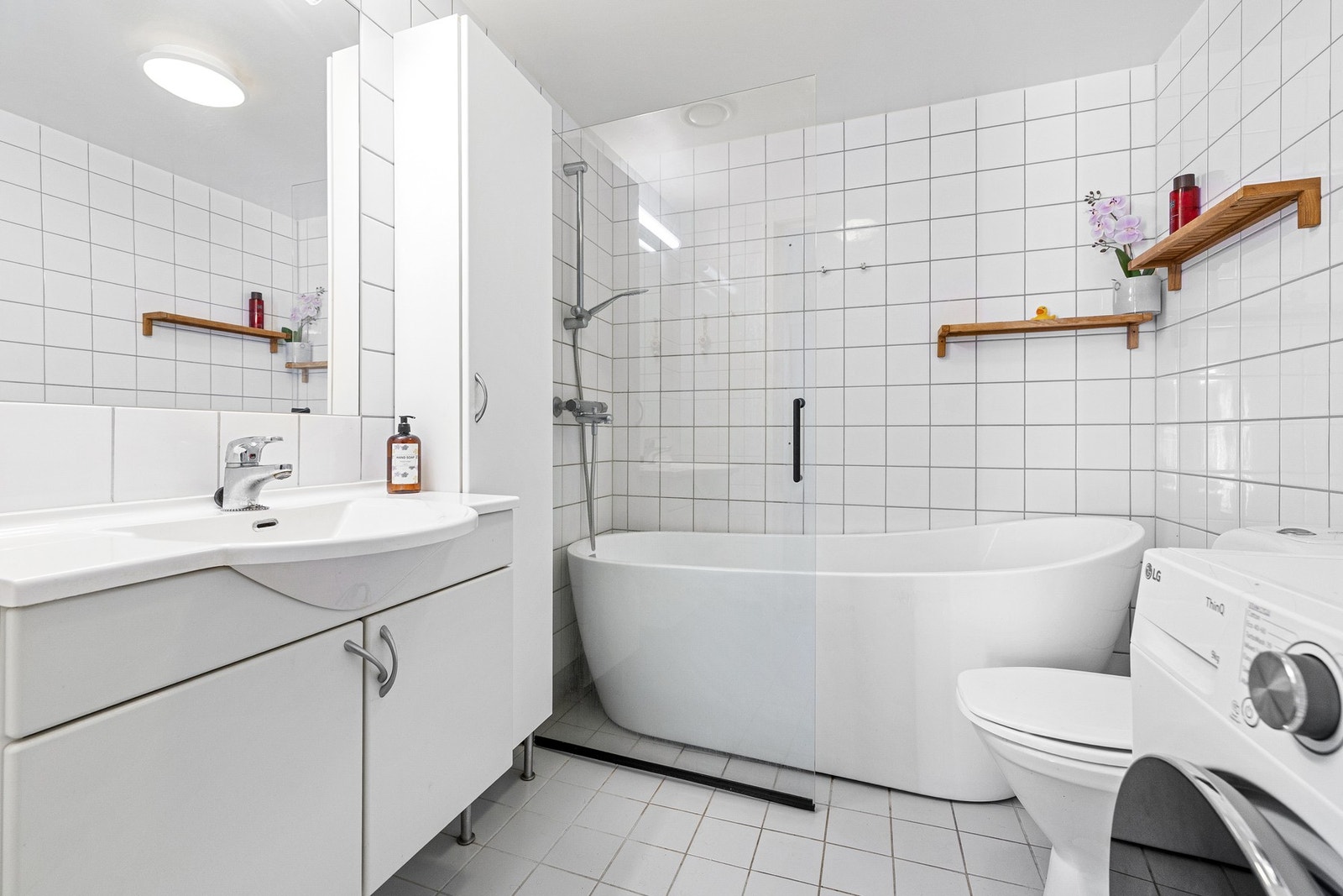 Flislagt bad med varmekabler i gulvet. Servantseksjon med skap, speil og opplegg for vaskemaskin. Galleribilde