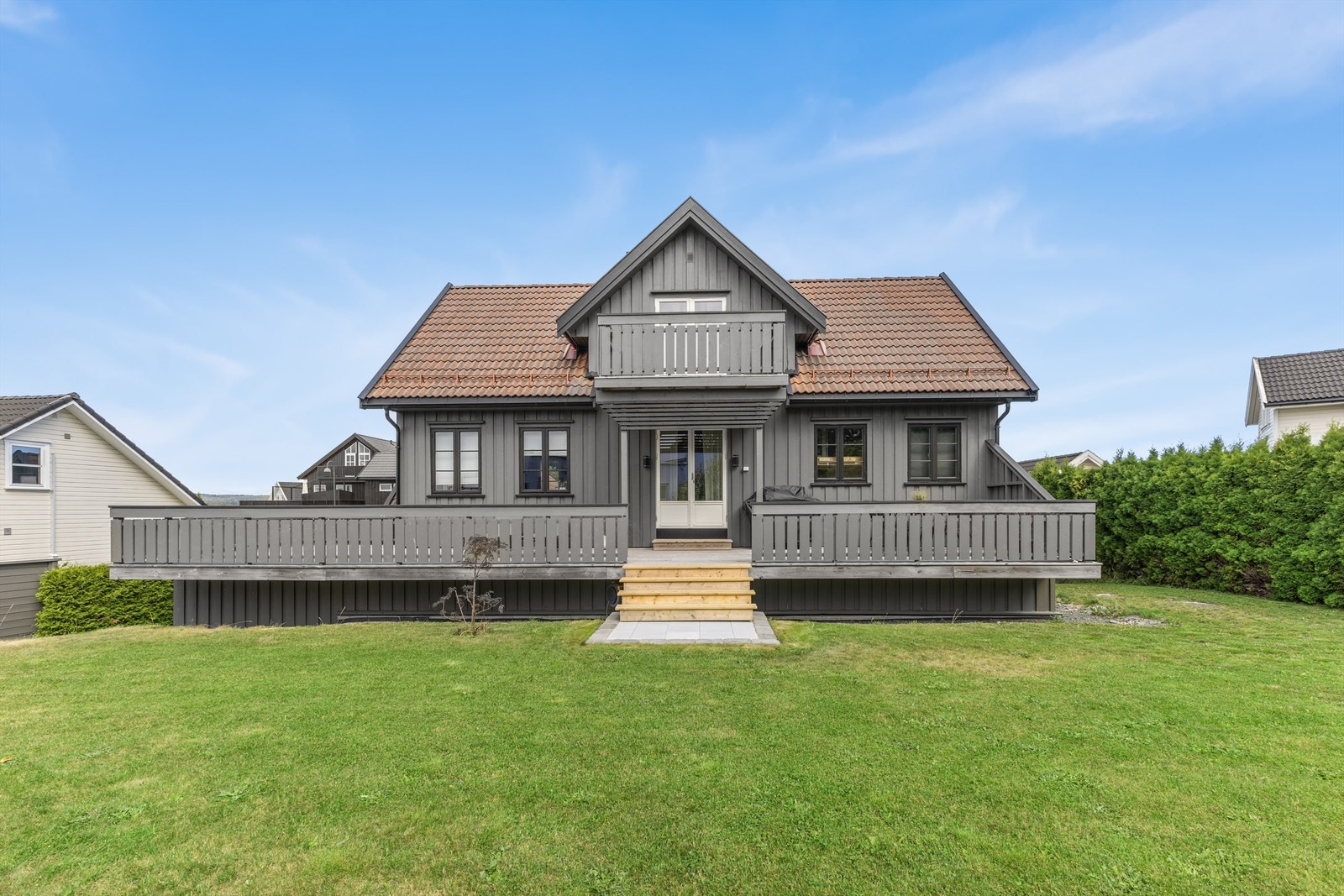 Fin uteplass med veranda og plen på fremsiden av boligen Galleribilde