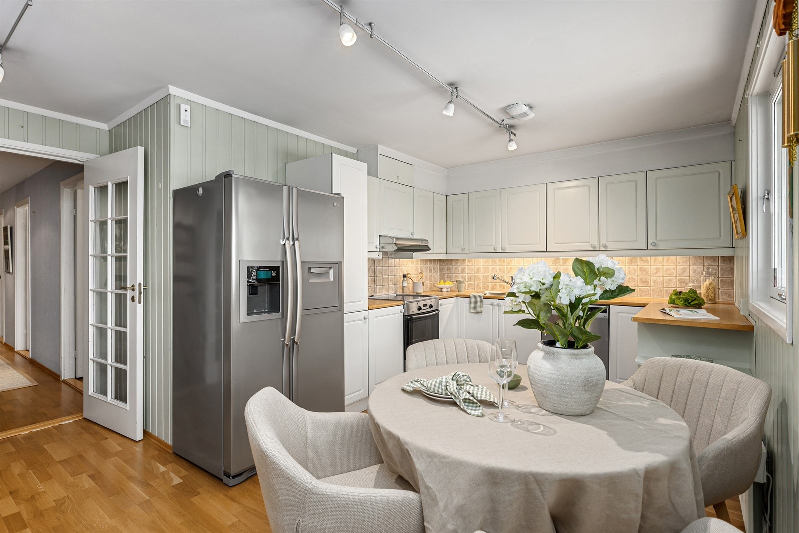 Kjøkkenet er pent holdt, med hvite profilerte fronter og frittstående hvitevarer som medfølger leiligheten Galleribilde