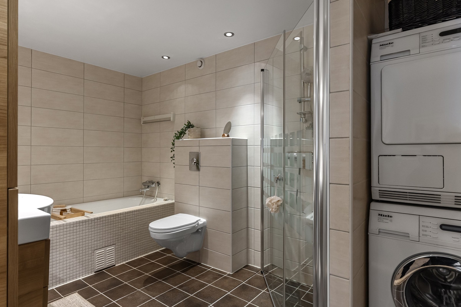 Ved siden av dusjnisjen er det satt opp en vegg som fungerer som romavdeler for vaskemaskin og tørketrommel i søyle Galleribilde