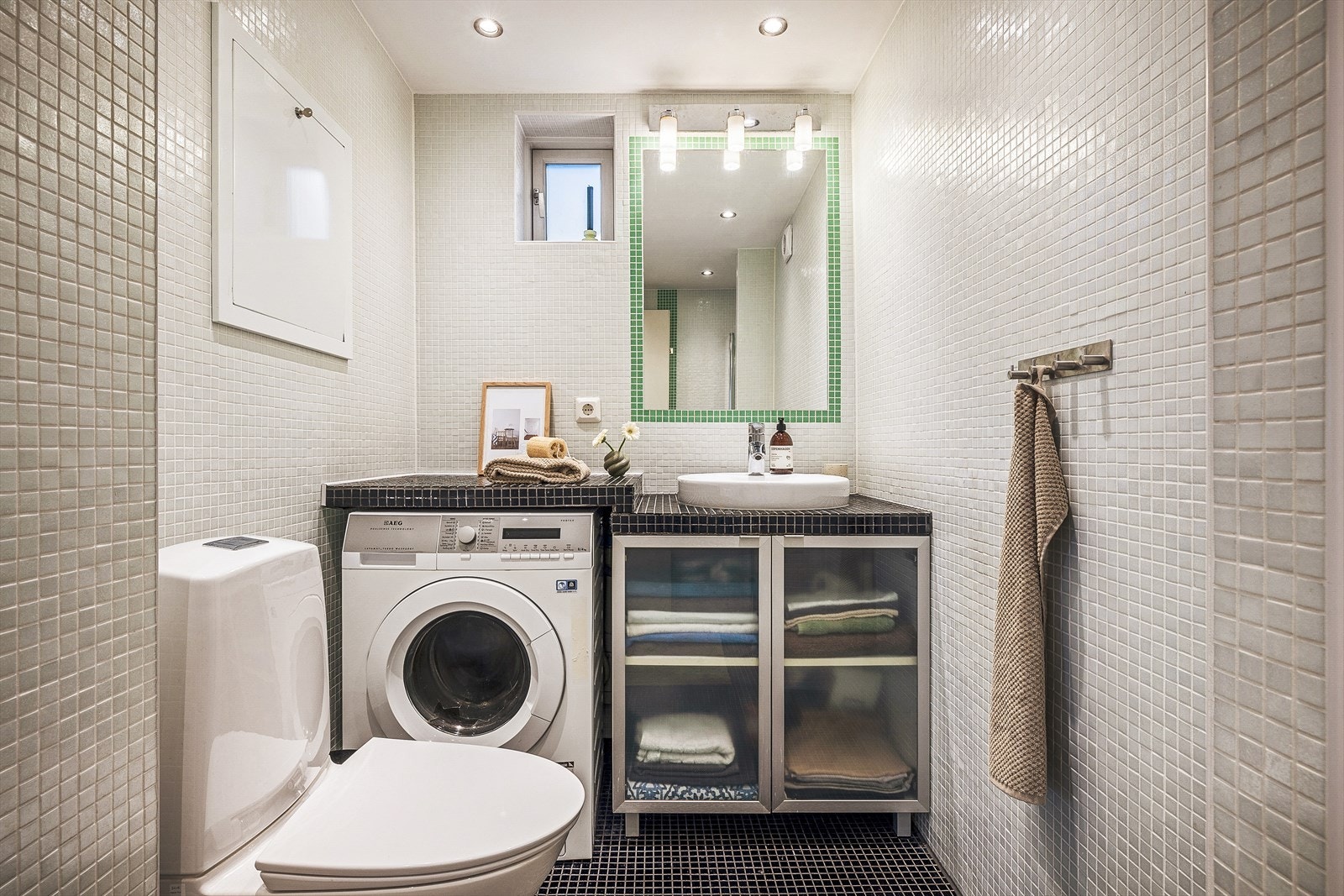 Badet inneholder bla fliser på både gulv og vegger, servant, toalett og vaskemaskin. Galleribilde