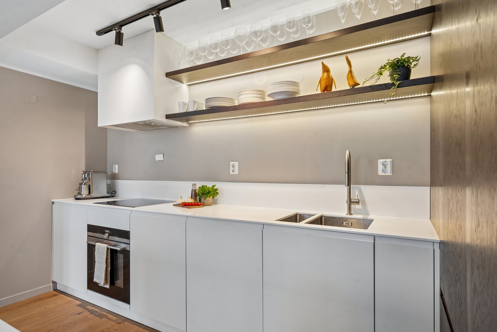 Pent, plassbygd kjøkken med slette fronter, Corian benkeplate og integrerte hvitevarer Galleribilde