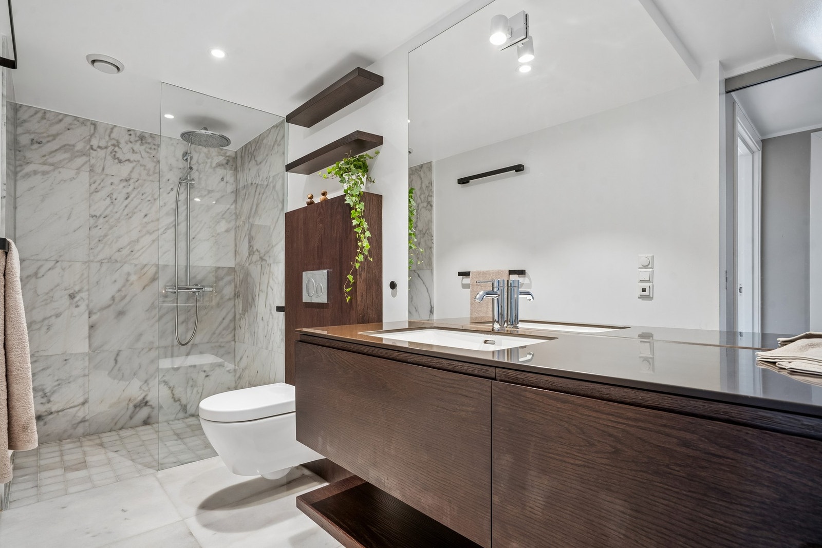 Lekkert og innbydende bad med marmor på gulv og i dusjsone. Badet inneholder plassbygd innredning med Corian benkeplate, toalett, dusjhjørne, speil og belysning. Rommet har varmekabler Galleribilde