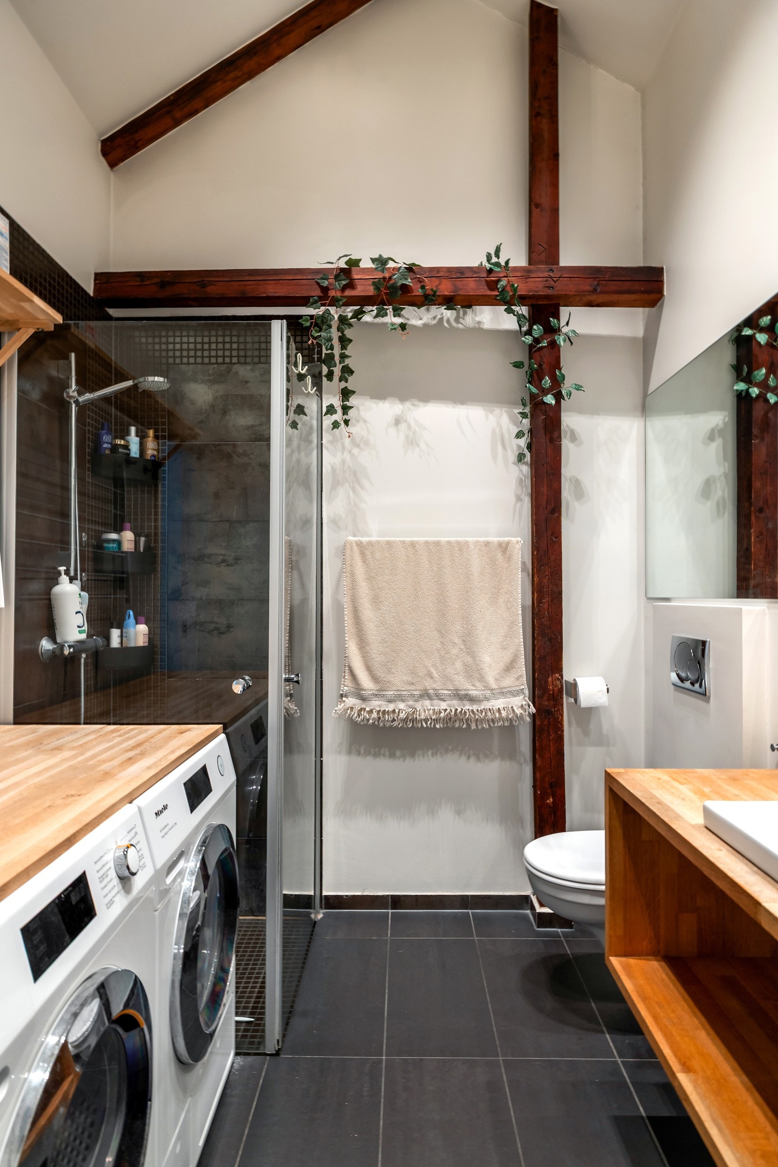 Rommet har vegghengt toalett, dusjhjørne med glassdører og praktisk opplegg for vaskemaskin og tørketrommel. Galleribilde