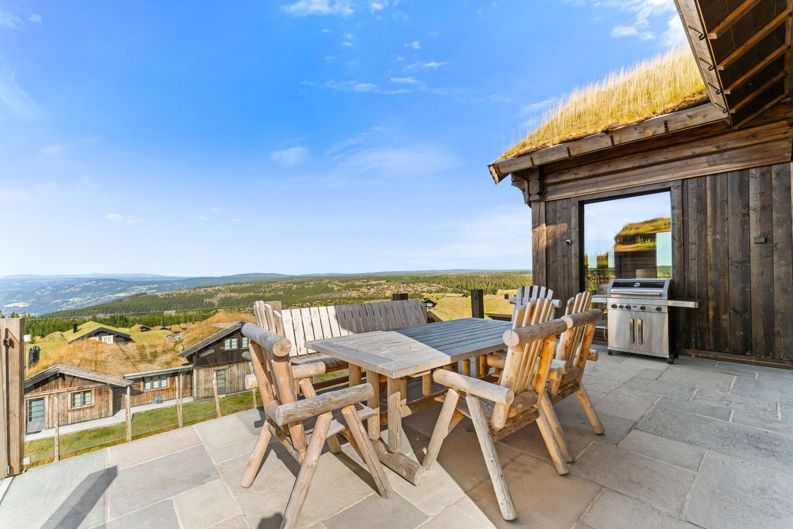 En stor og meget solrik terrasse omkranser hytta mot syd og vest - fantastisk utsikt fra hele terrassen og praktisk adkomst også via gårdsplass Galleribilde
