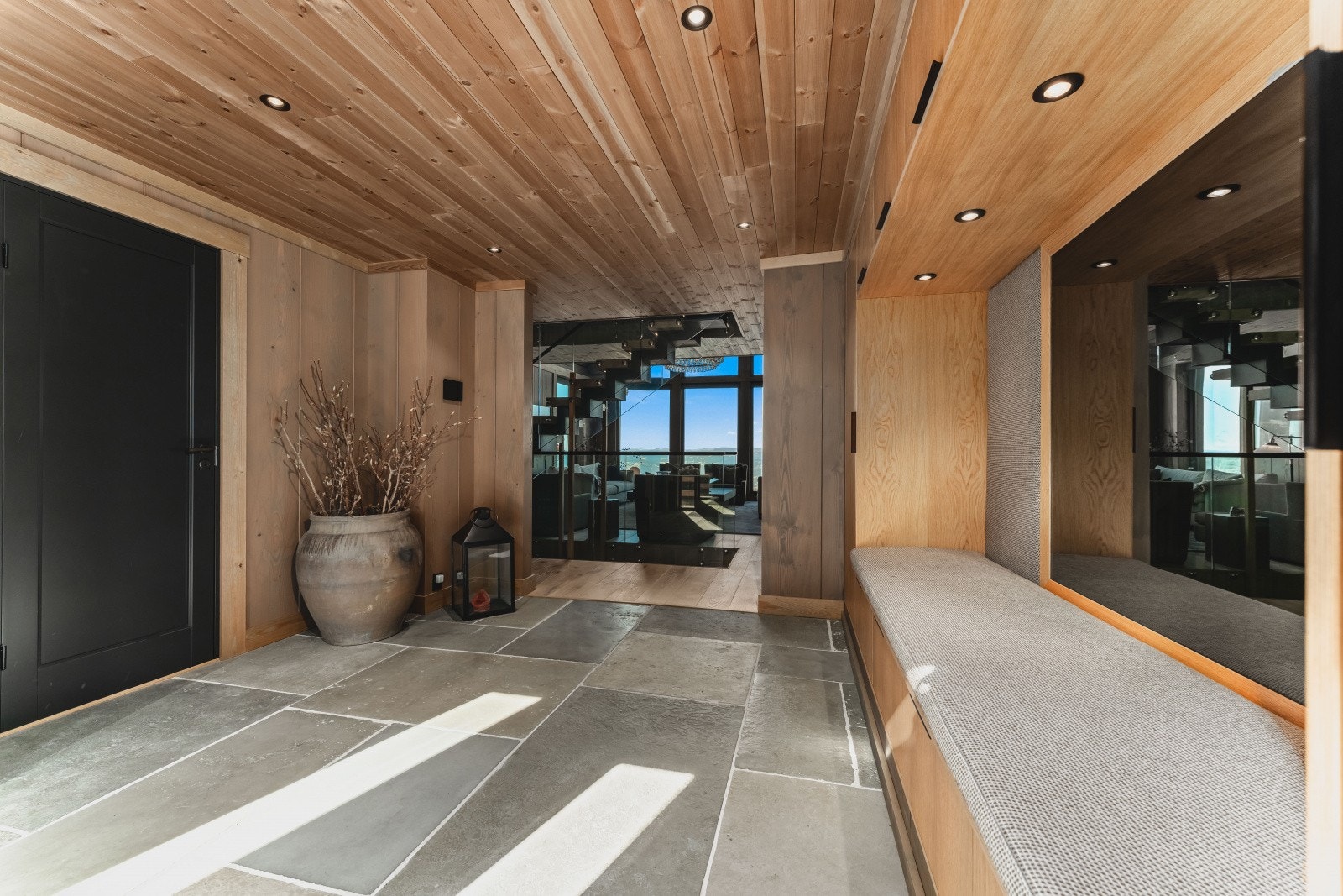 Representativ og romslig hall med utsikten tvers gjennom bygningen med det samme du ankommer hytta! Diverse garderobeplass, sittebenk mm. Eksklusive Raw Stone fliser Galleribilde