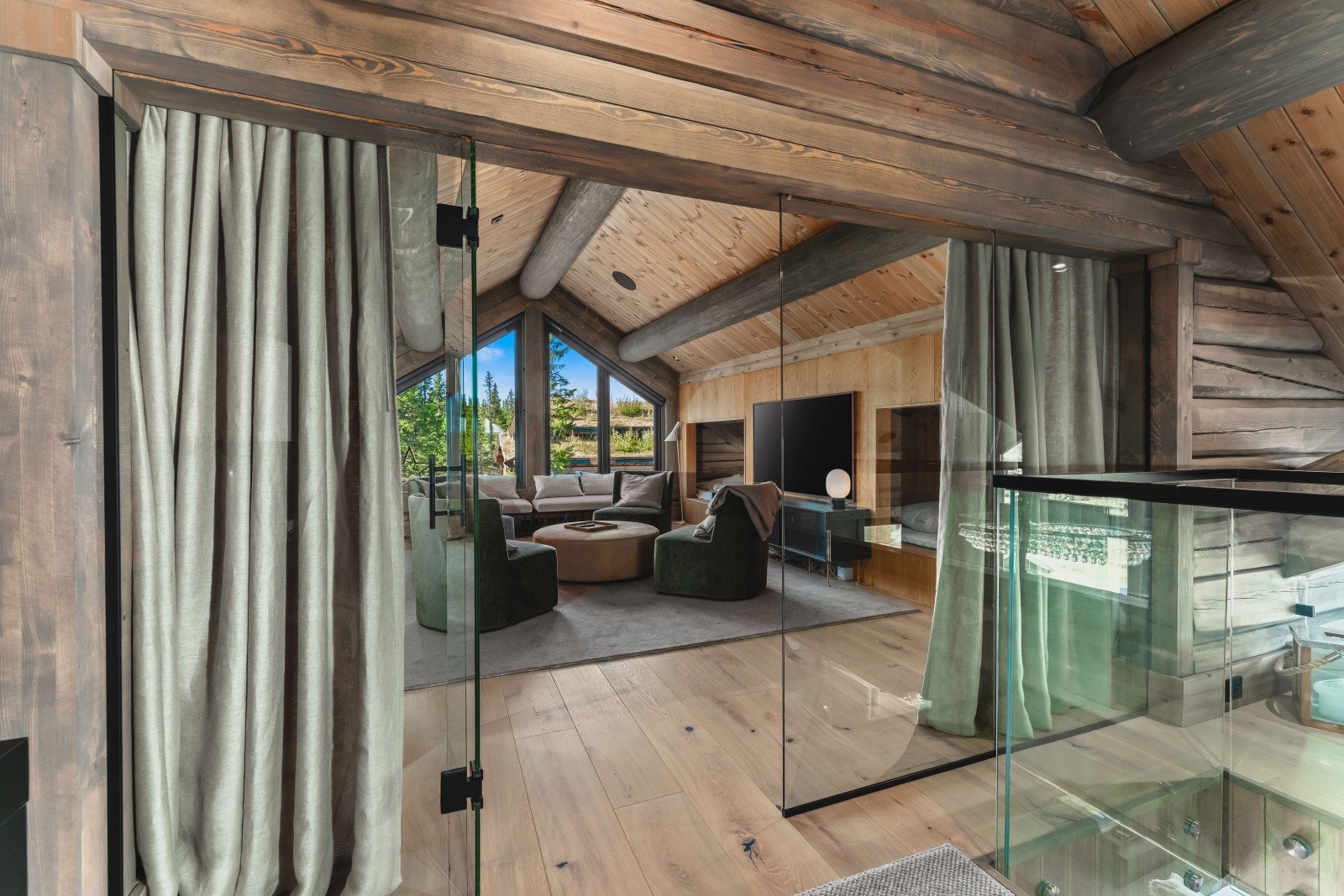 Glassvegg og dør inn til stuen i 2. etg. ivaretar også flott gjennomlys og utsikt. Rommet fungerer også alternativt som hyttas soverom nr. 9! med 4 stk. koselige plassbygde senger Galleribilde
