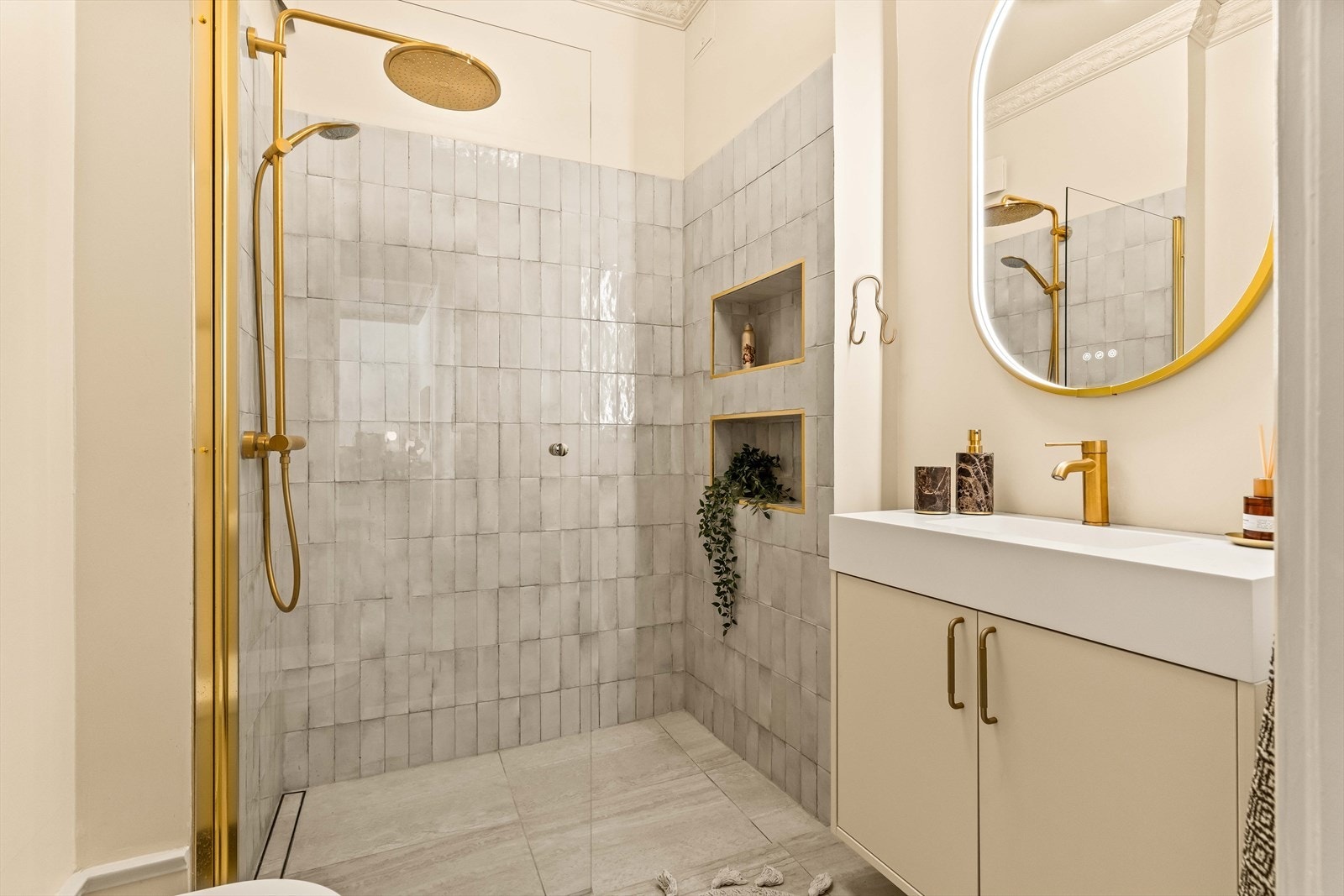 Leilighetens andre bad ble også omfattende pusset opp i 2025. Her er det flislagt gulv med varmekabler, og en dusjsone med stilfulle, vertikale fliser og innfelte nisjer. Galleribilde