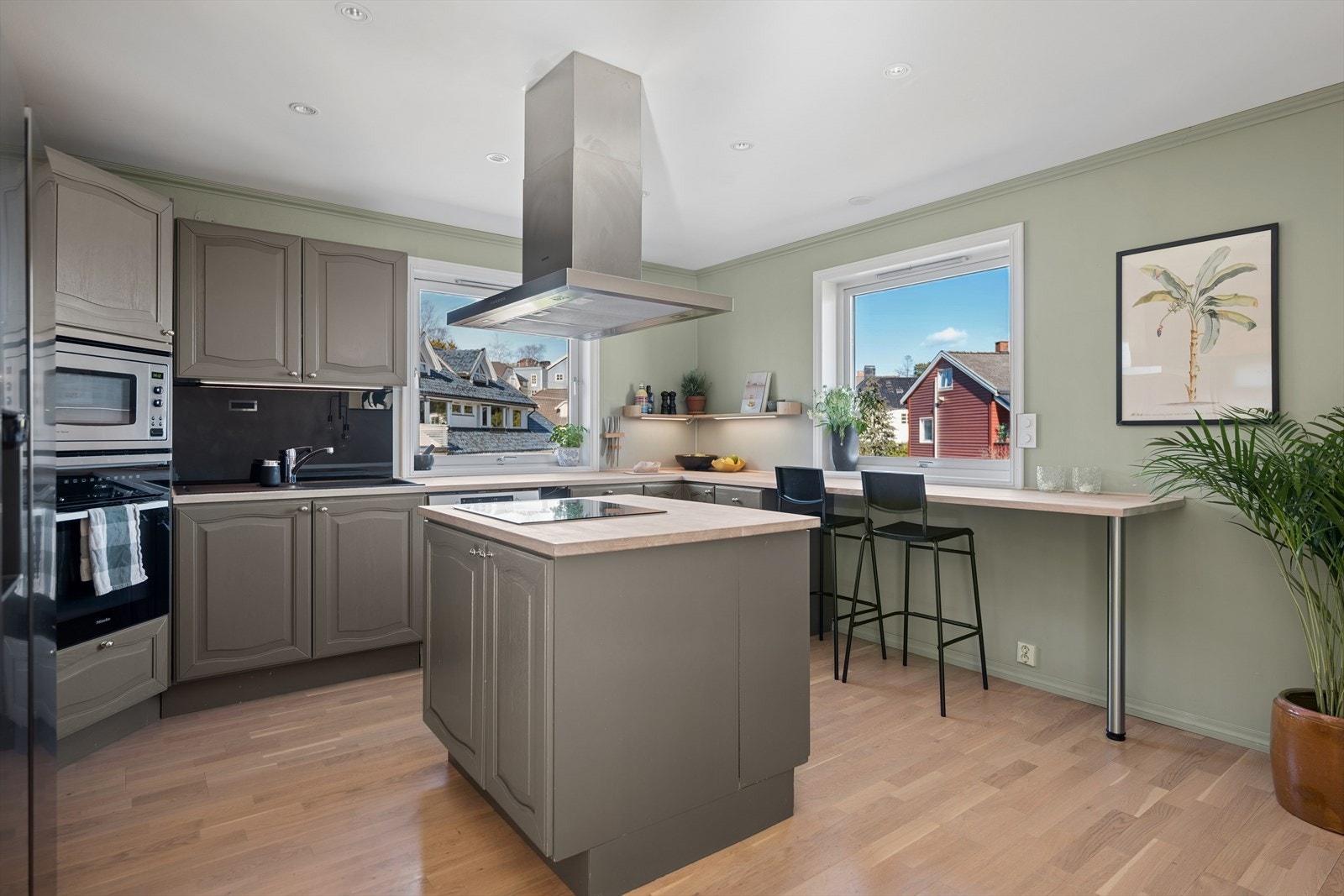 Et romslig og funksjonelt kjøkken med kjøkkenøy, god skapplass og naturlig sitteplass ved vinduet - perfekt for både hverdagsliv og sosiale sammenkomster. Galleribilde