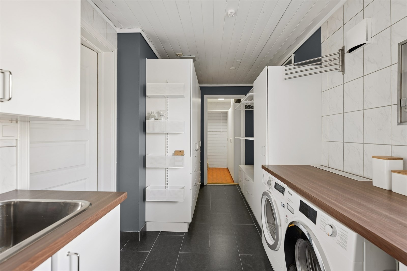 Romslig og praktisk vaskerom med god benkeplass, opplegg for vask og tørk samt rikelig med oppbevaring. Galleribilde