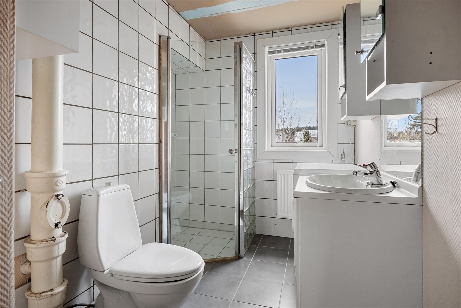 Eldre bad med dusjhjørne, servant m/tilhørende innredning og wc. Galleribilde