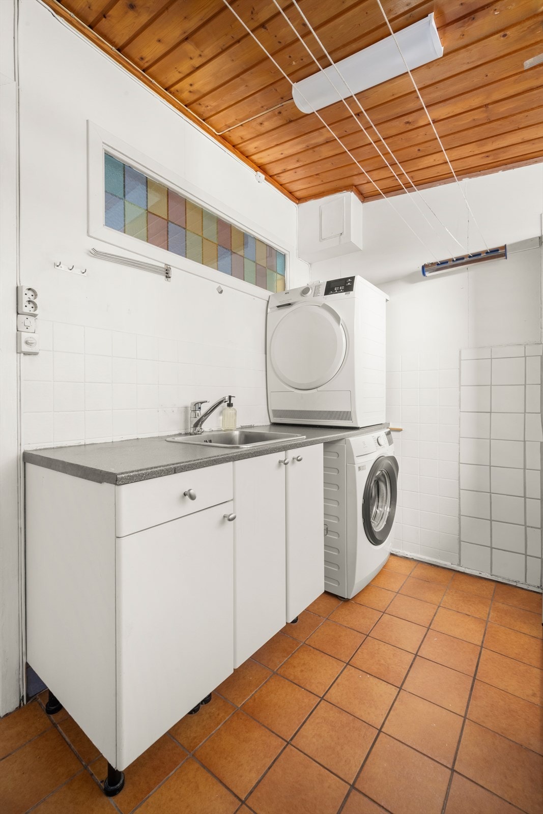 Praktisk bad og vaskerom i første etasje med flislagt gulv med gulvvarme og opplegg for vaskemaskin. Rommet har en enkel standard og behov for oppgraderinger. Galleribilde