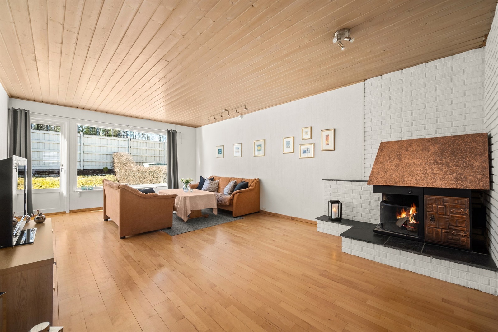 Romslig stue med åpen peis som gir en lun atmosfære. Gulvet er belagt med parkett. Galleribilde