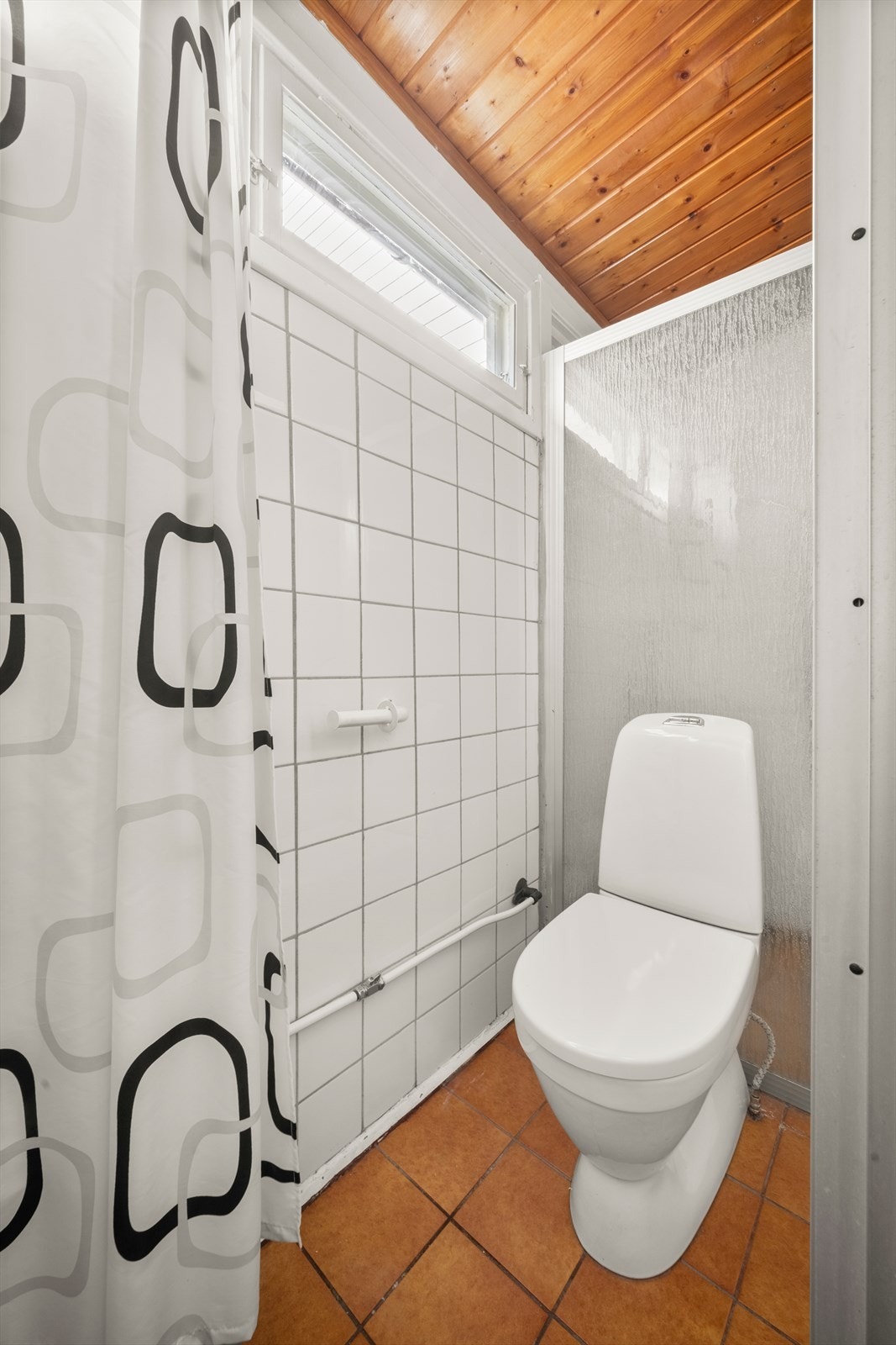 Rommet inneholder også et gulvstående toalett og en dusjnisje med skyvedør. Galleribilde