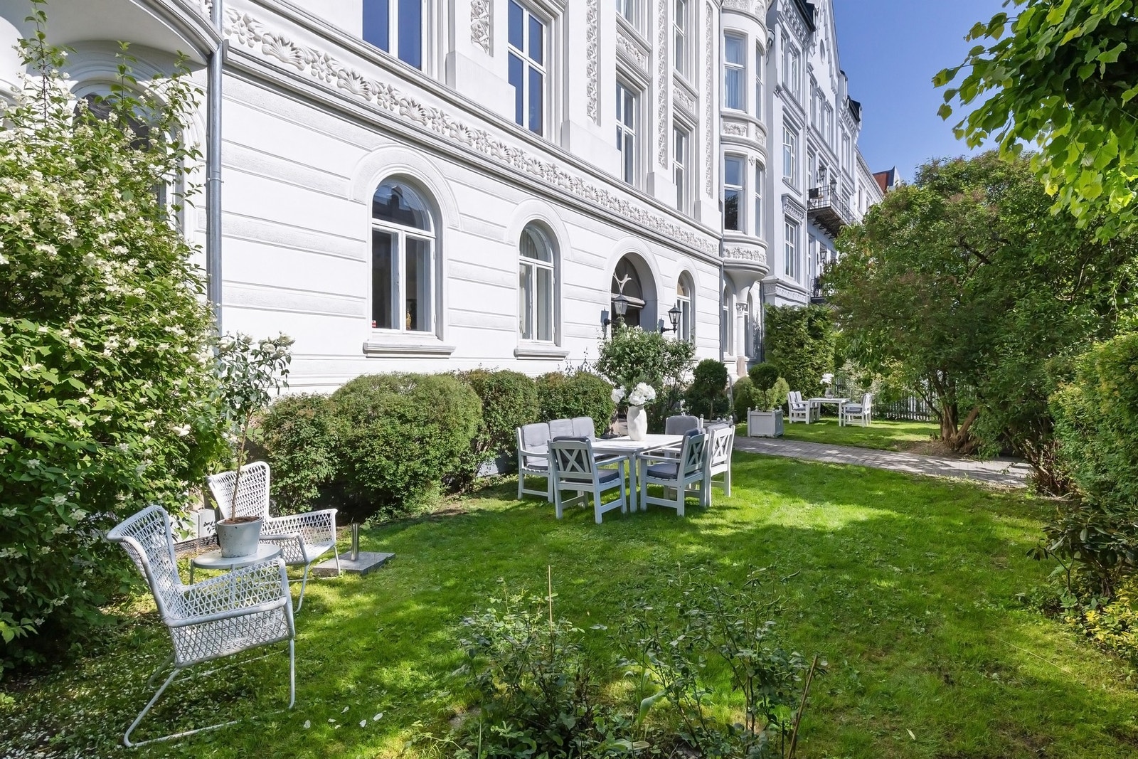 Stor og frodig felleshage i front, avgrenset av gjerdet med mekanisk port mot gaten. (Arkivbilde) Galleribilde