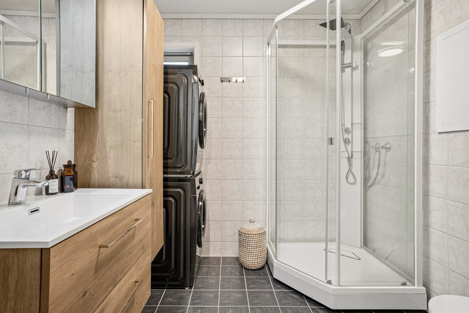 Badet er utstyrt med flislagt gulv med gulvvarme, dusjkabinett og opplegg for vaskesøyle. Galleribilde