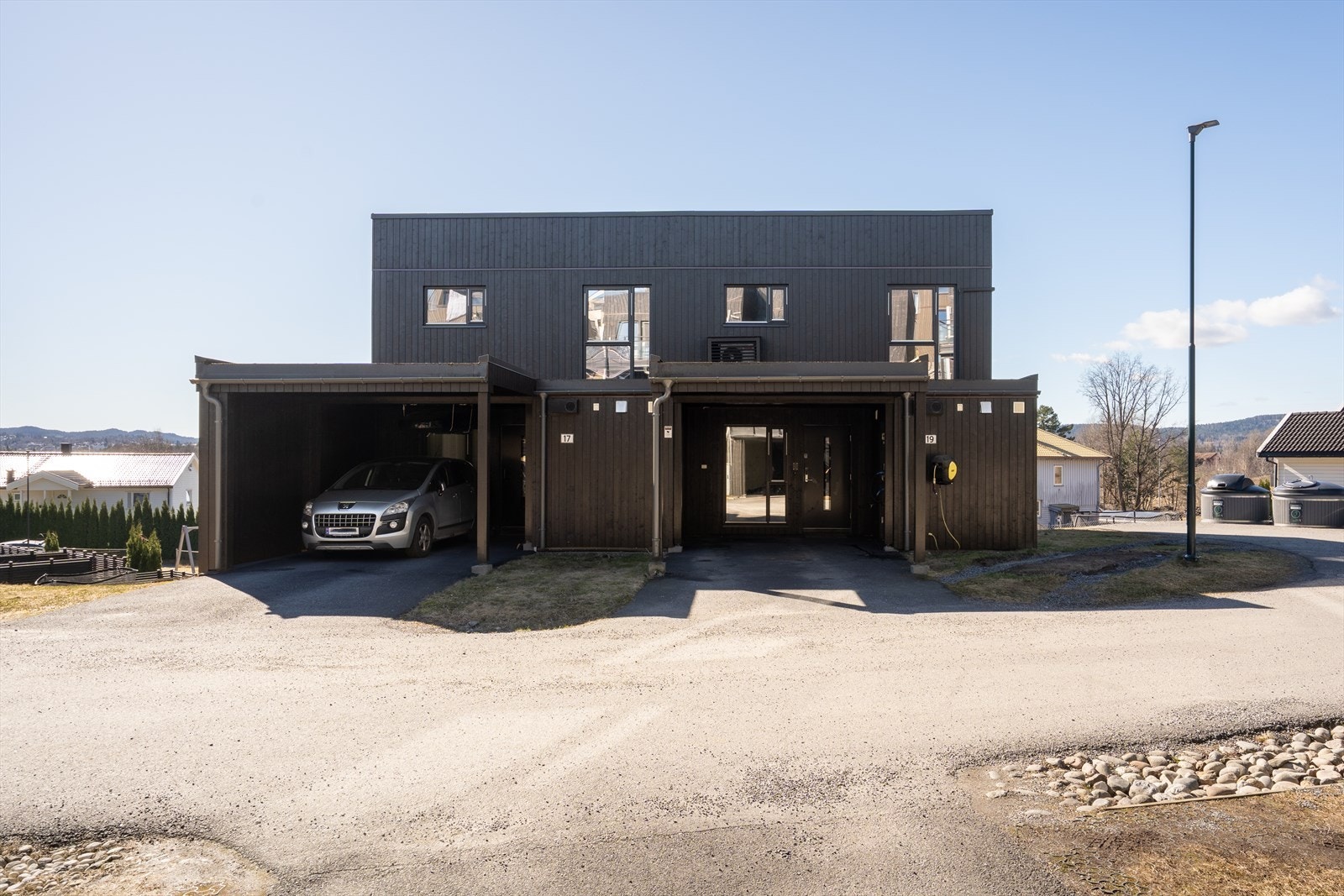 Ved inngangen har boligen en asfaltert carport med bod, belysning og en lader for elbil montert i 2023. Galleribilde