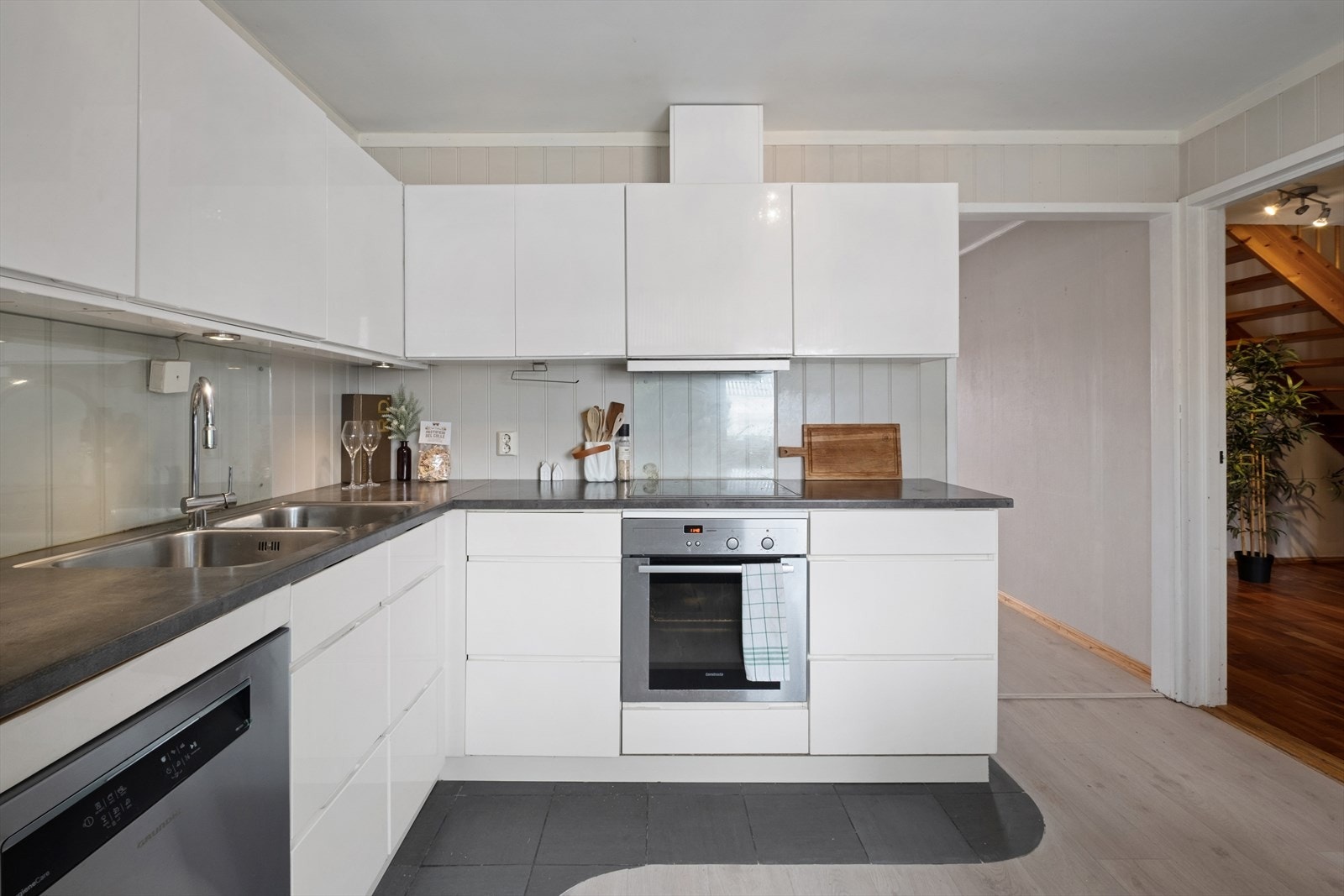 Lekker og lys kjøkkeninnredning med glatte fronter, dobbel oppvaskkum med ett-greps blandebatteri og ventilator over kokesonen. Galleribilde