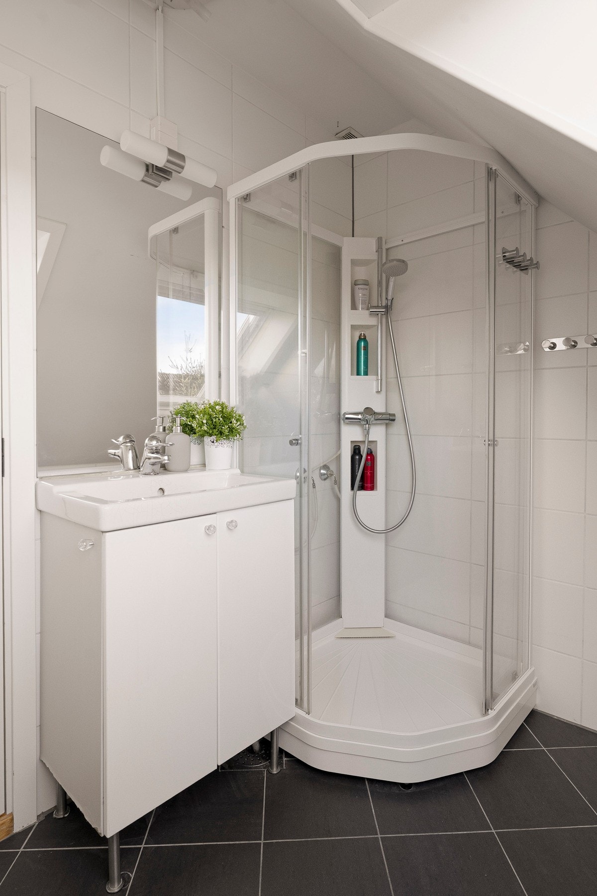 Badet er utstyrt med dusjkabinett, servant med underskap og gode oppbevaringsmuligheter. Galleribilde