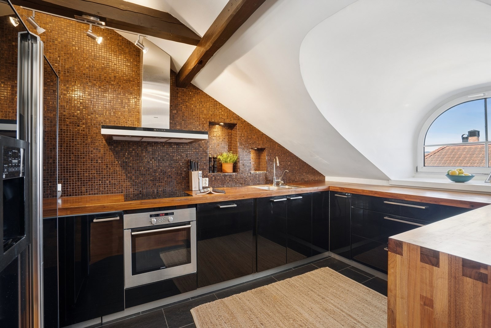 Flislagt bakvegg og integrert belysning gir et gjennomført og stilrent uttrykk, og det er behagelig varme i gulvet fra varmekabler. Galleribilde