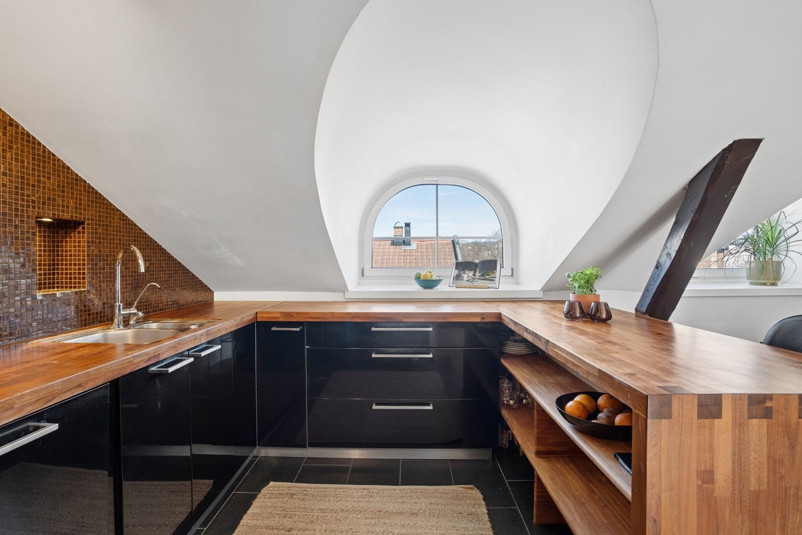 Kjøkkenet er godt utnyttet med gode arbeidsflater og en praktisk barløsning, som gir en naturlig overgang til stue og spiseplass. Innredningen er utstyrt med integrert koketopp, stekeovn og oppvaskmaskin, samt frittstående side-by-side kjøl-/fryseskap. Galleribilde