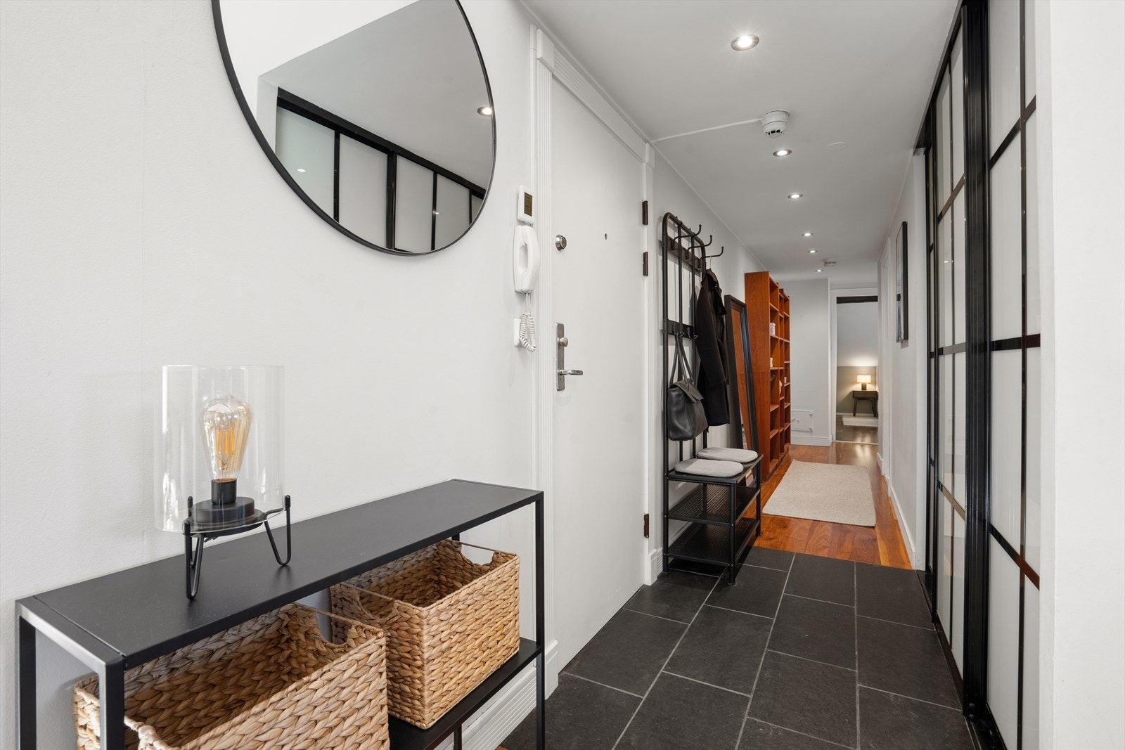 Her ønskes du velkommen inn i en innbydende entré med praktiske fliser på gulv og behagelig varme fra varmekabler. Det er god plass til oppbevaring av yttertøy og sko i en romslig skyvedørsgarderobe. Galleribilde