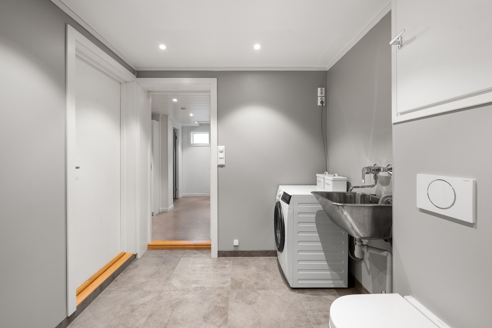 Dette rommet kombinerer funksjonene til et bad og vaskerom, og har adkomst fra gangen i underetasjen. Galleribilde