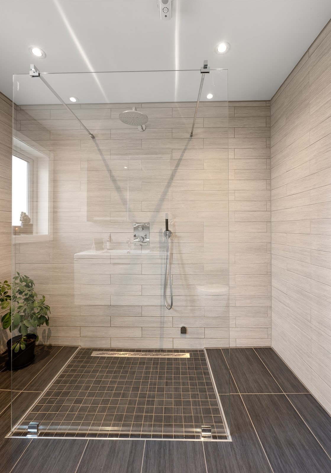 Den romslige dusjsonen er utstyrt med regnfallsdusj og adskilt med en dusjvegg i glass. Galleribilde