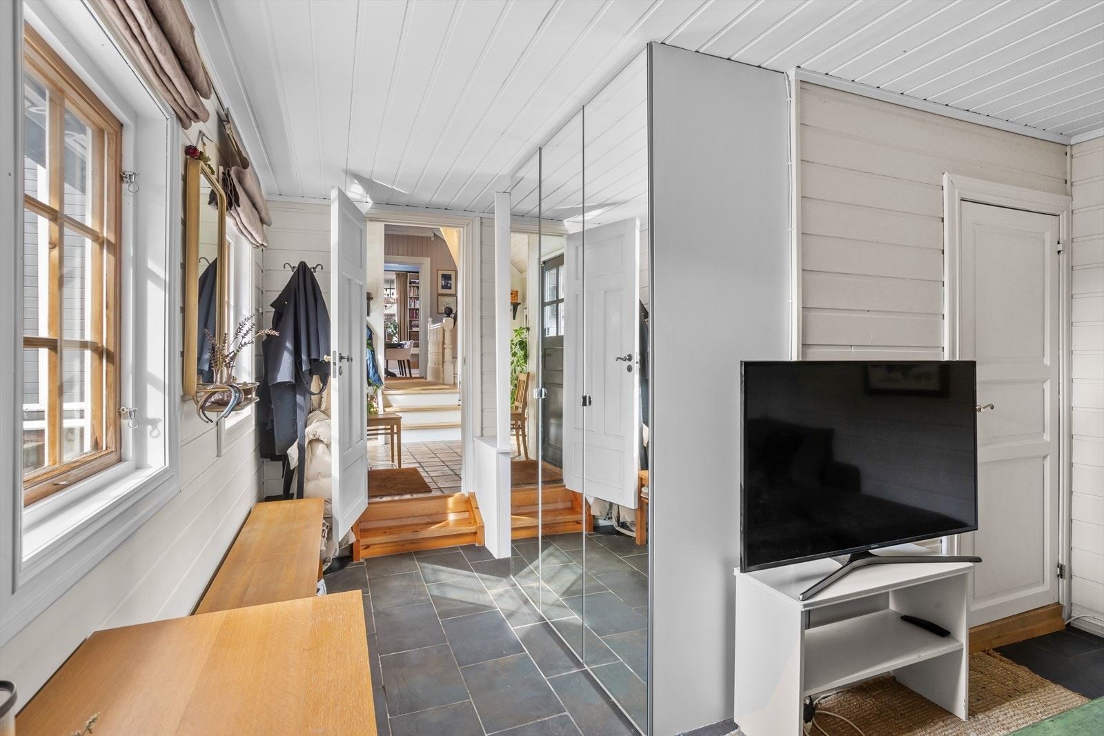 Den mindre stuen/soverommet med åpen gang er et mindre og flerbruksvennlig rom, tilbaketrukket fra øvrige hovedoppholdsrom i hjemmet. I tre-dørs takhøyt garderobeskap med speildører kan yttertøy og annet ryddes pent vekk. Galleribilde