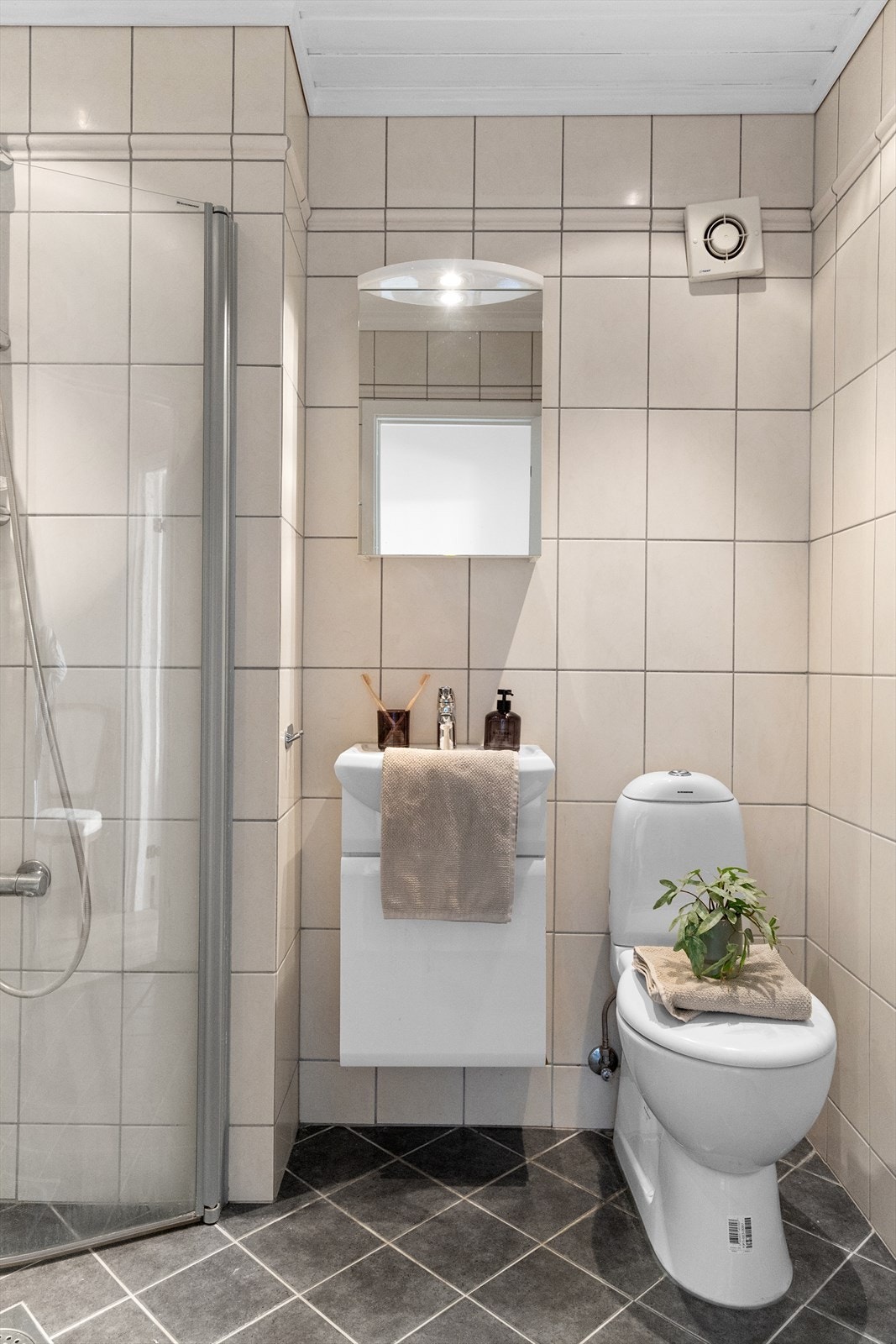 Flott helfliset bad med varmekabler. Badet er innredet med servant med underskap + overskap med speil og stikkontakt, dusjhjørne i glass og wc. Galleribilde