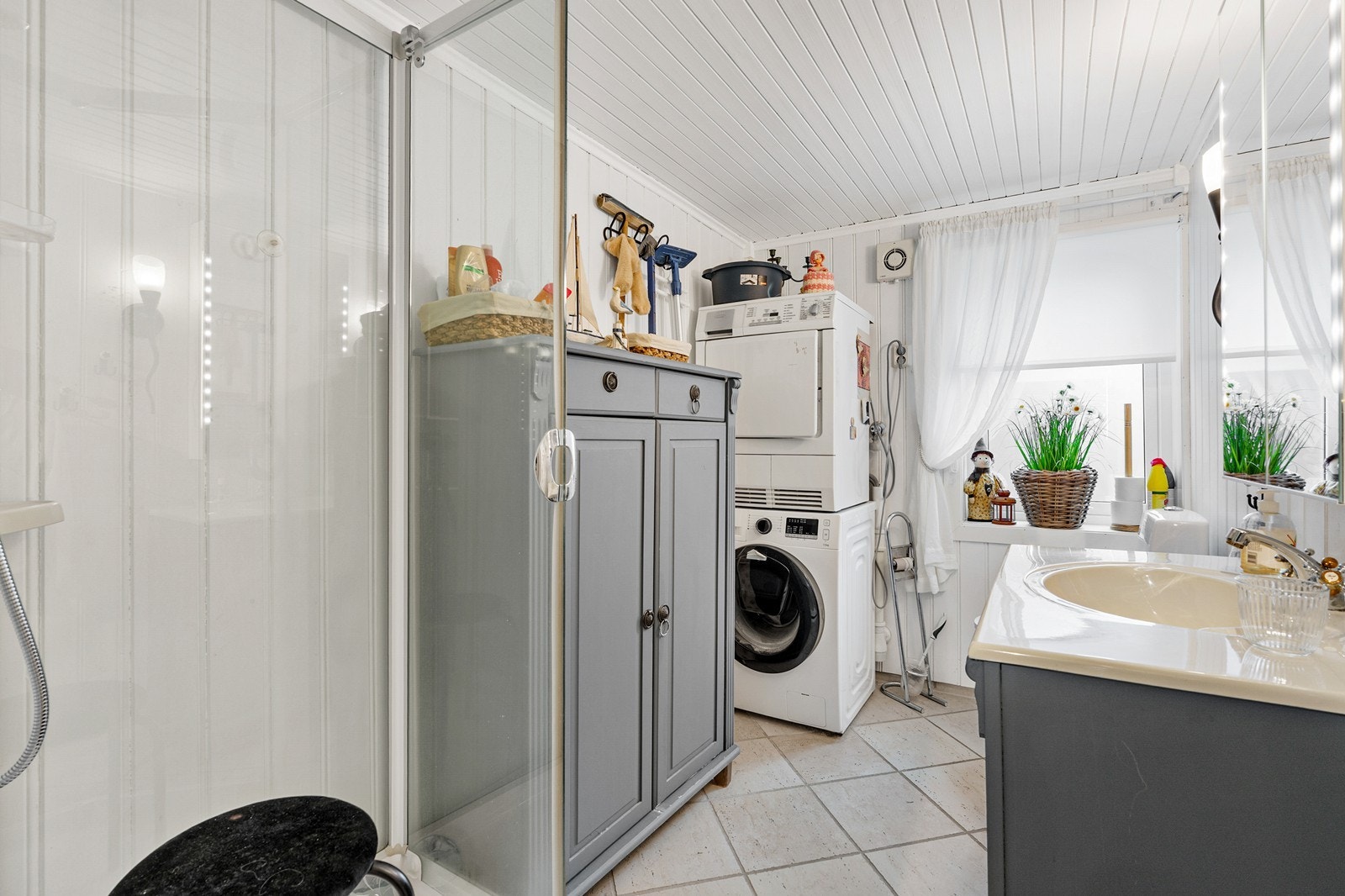 Badet er utstyrt med dusjkabinett, gulvstående toalett, vask med skapinnredning og speilskap Galleribilde