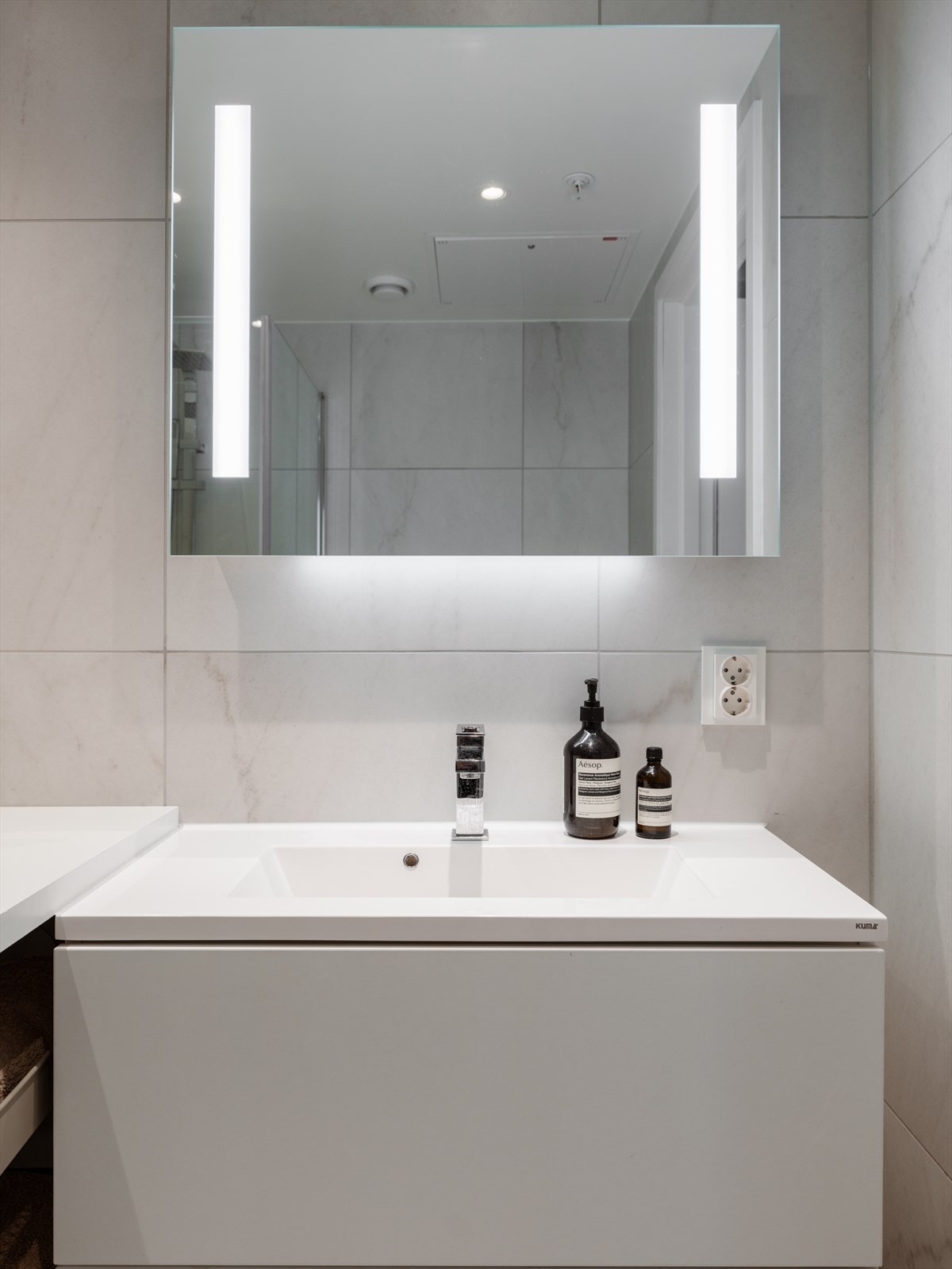 Moderne innredning med servantskap, speil med integrert lys, vegghengt toalett og opplegg for vaskemaskin. Galleribilde