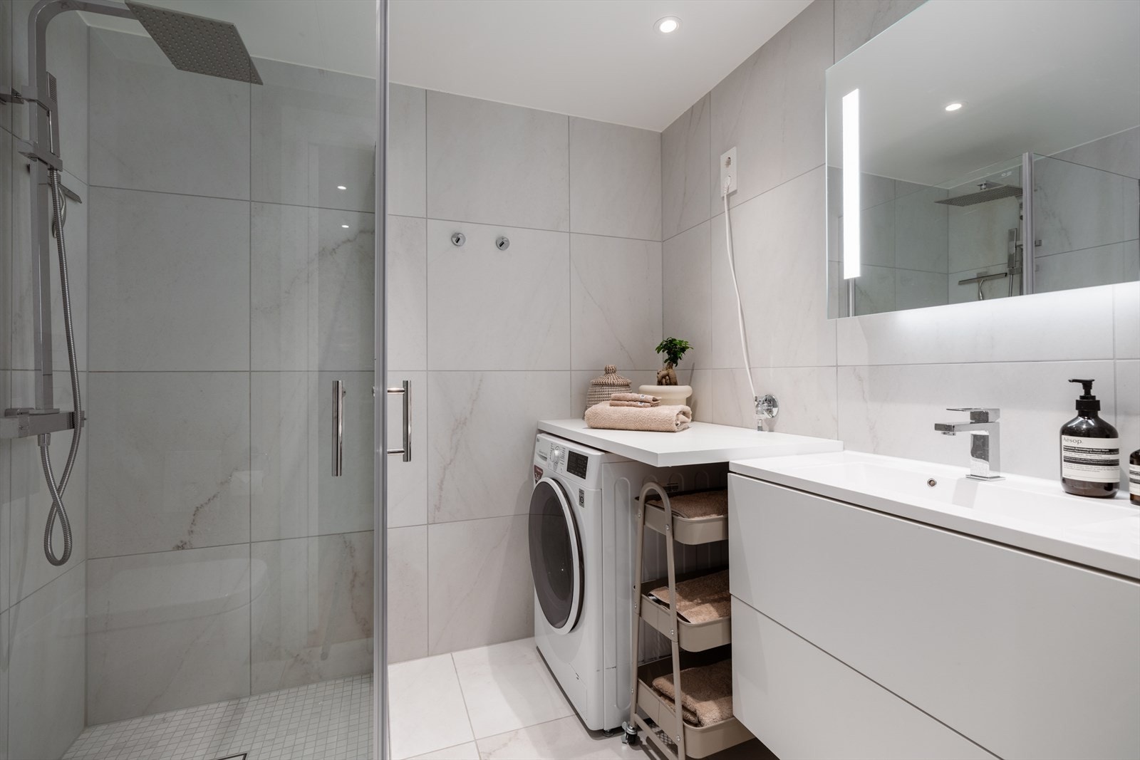 Lekkert flislagt bad med moderne og stilrent flis- og fargevalg, downlights i taket og behagelig vannbåren gulvvarme. Galleribilde