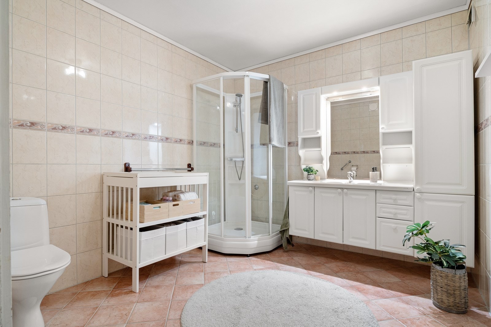 Badet er utstyrt med dusjkabinett, servant med møblement og wc. Galleribilde