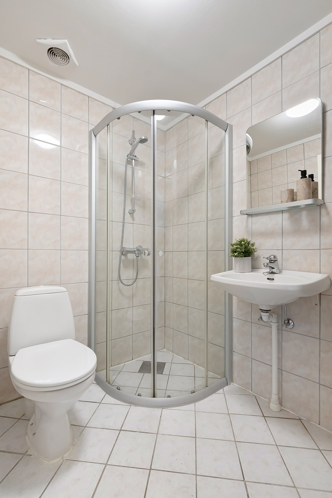 Flislagt baderom med toalett, servant og dusjhjørne. Galleribilde