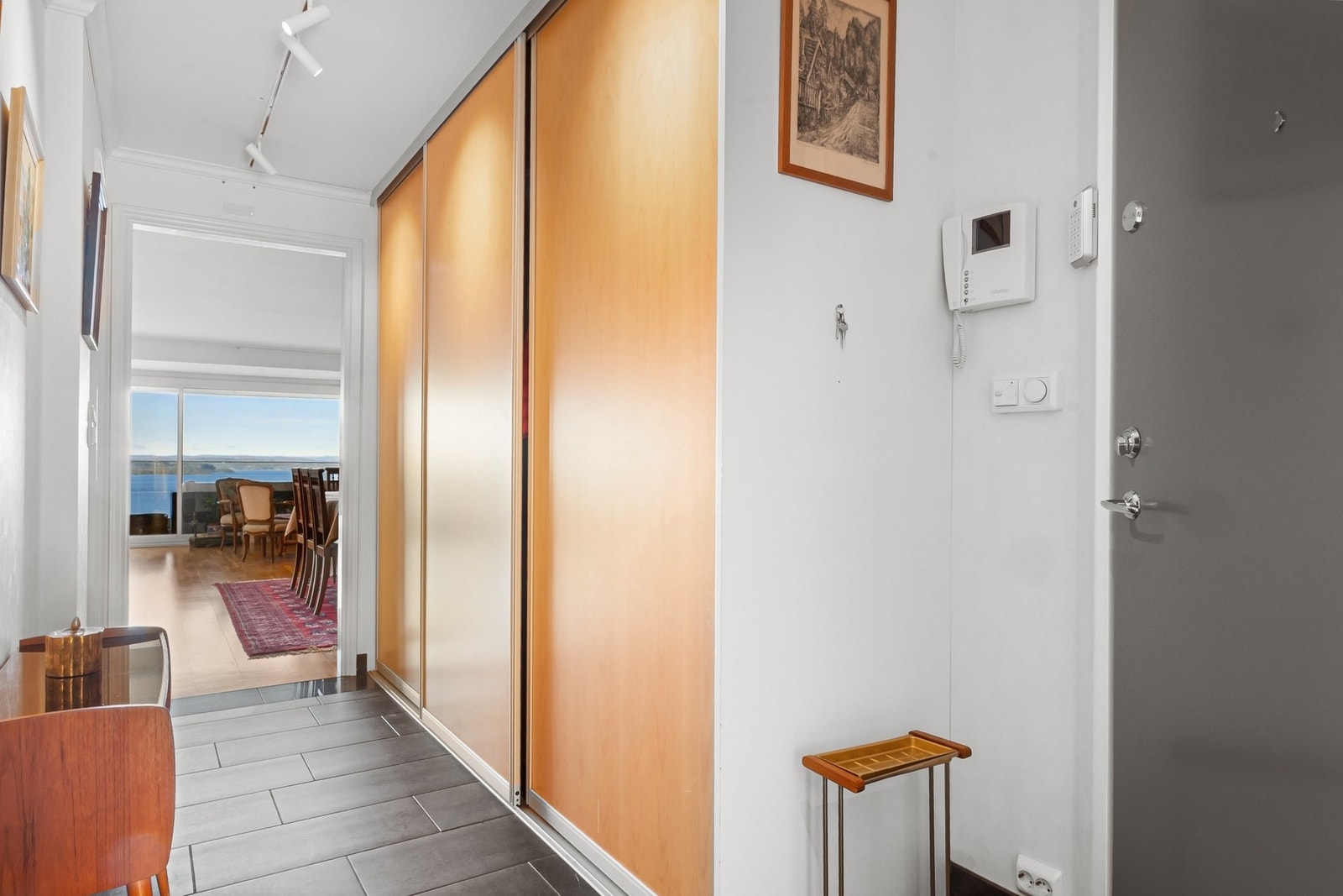Romslig entré med flislagt gulv og praktisk skyvedørsgarderobe med god oppbevaringsplass. Galleribilde