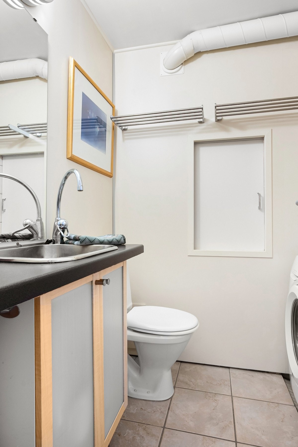 Svært praktisk WC i tilknytning til entréen. Rommet ble oppusset av tidligere eier i 2016 og har flislagt gulv med varme. Inneholder gulvmontert toalett, servantseksjon med skap, speil samt opplegg for vaskemaskin. Galleribilde