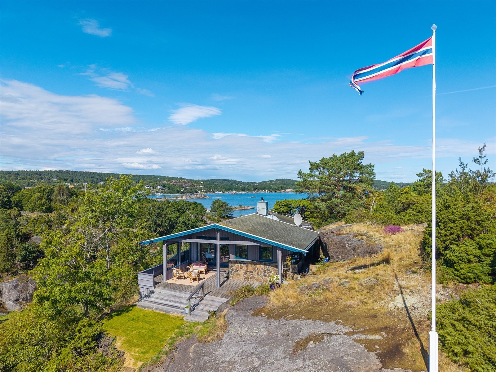 Denne flotte fritidseiendommen fra 1971 ligger høyt og fritt til, med en spektakulær sjøutsikt både mot nord og sør. Her får du sol fra morgen til kveld, vakre uteplasser og en planløsning som er både praktisk og sosial - perfekt for sommerliv med familie Galleribilde