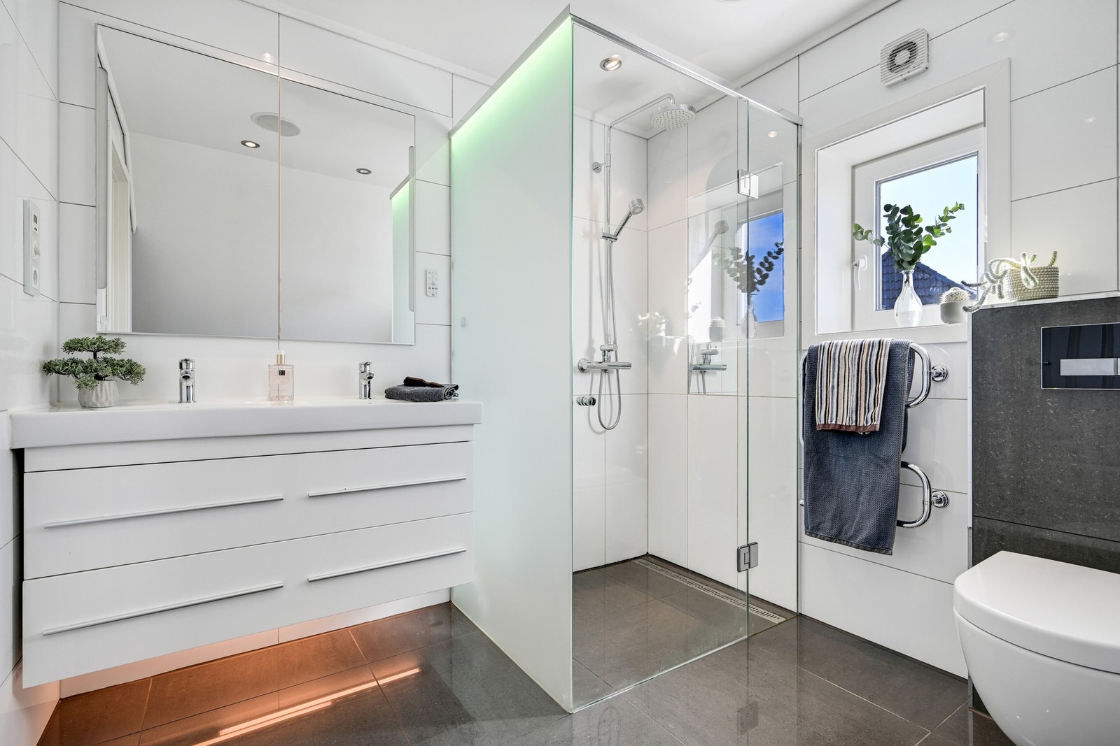 Badet inneholder dobbelservant, veggmontert wc, håndkletørker og dusjhjørne. Galleribilde