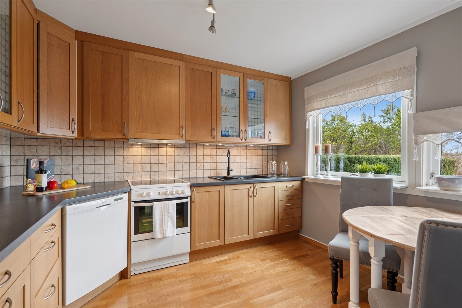 Velholdt kjøkken med profilerte fronter og rikelig med oppbevaringsplass i takhøye overskap og underskap Galleribilde