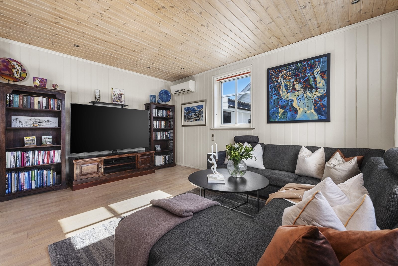 Stuen har parkett på gulv, lyse veggflater og en effektiv peisovn som gir god varme på kalde dager. Galleribilde