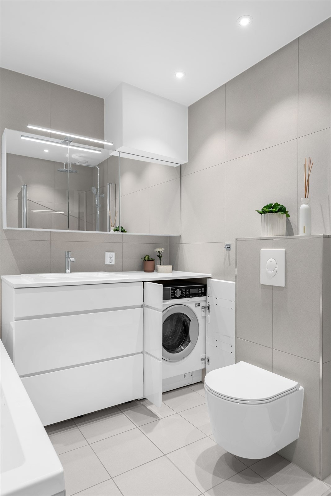 Speilskap med lys, servant med skuffer og plassbygget skapløsning for vanlig størrelse vaskemaskin under benk. Galleribilde