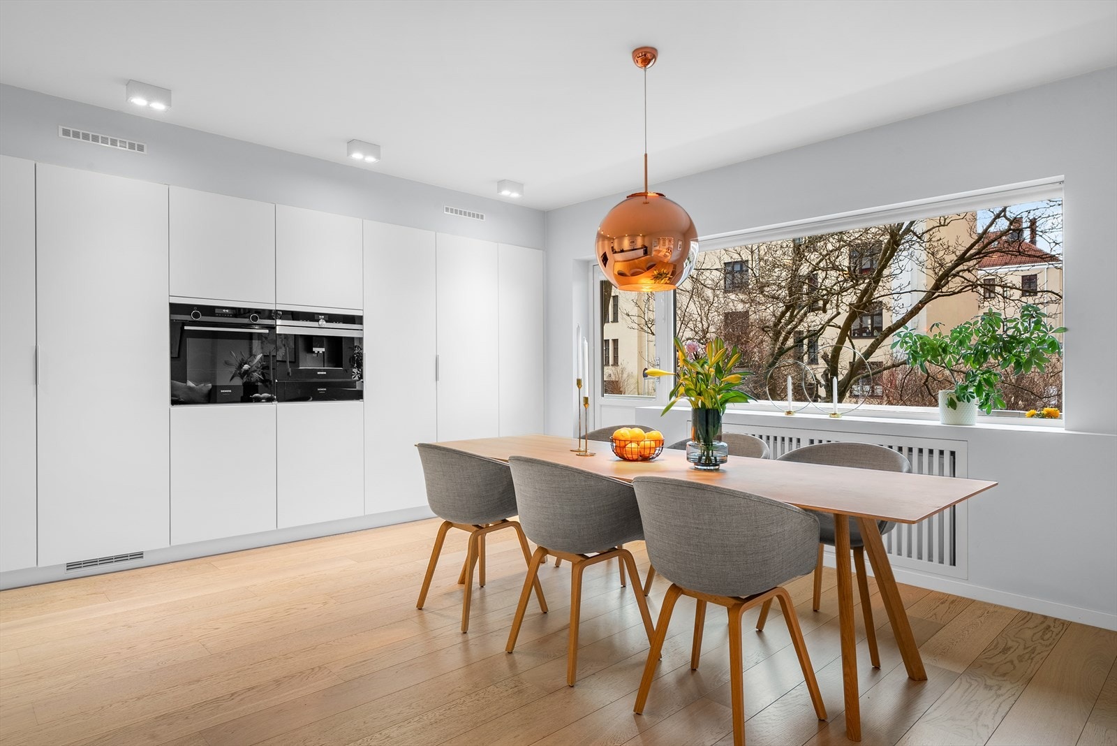 Innholdsrik vegg med integrerte høyskap og hvitevarer fra Siemens. Veggen inneholder høyskap med vaskeutstyr, høyskap med lagring, integrert fullsize fryseskap, kaffemaskin, varmeskuff, stekeovn, fullsize kjøleskap samt enda et høyskap med lagring. Galleribilde