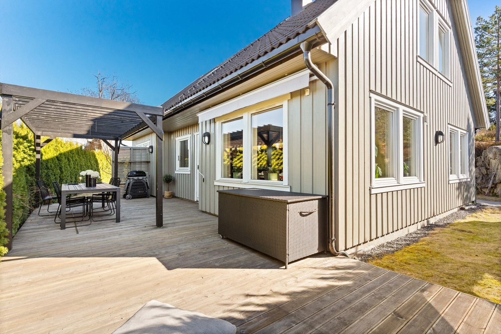 Romslig terrasse omkranset av hekk som gir en privat og lun atmosfære. Ideell for sosiale sammenkomster. Galleribilde