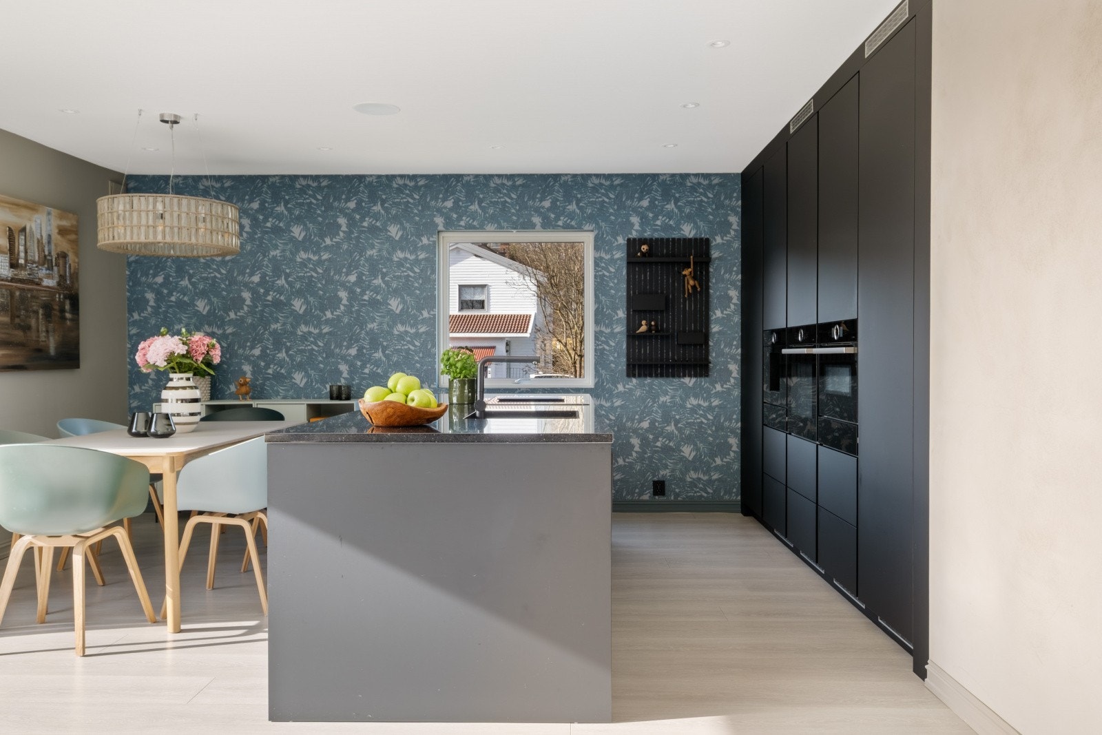 Moderne kjøkken med glatte fronter og gode arbeidsflater, plassert i åpen løsning mot stuen Galleribilde