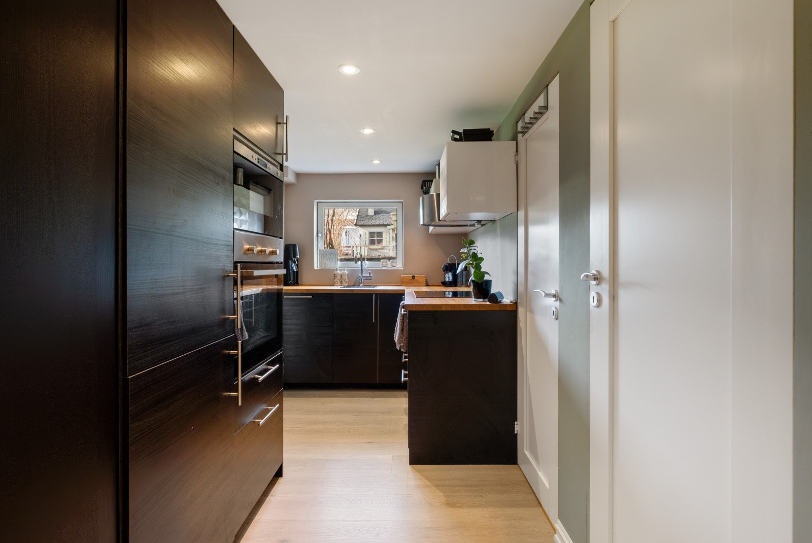 Moderne kjøkkeninnredning med glatte fronter, heltre benkeplate og ventilator Galleribilde