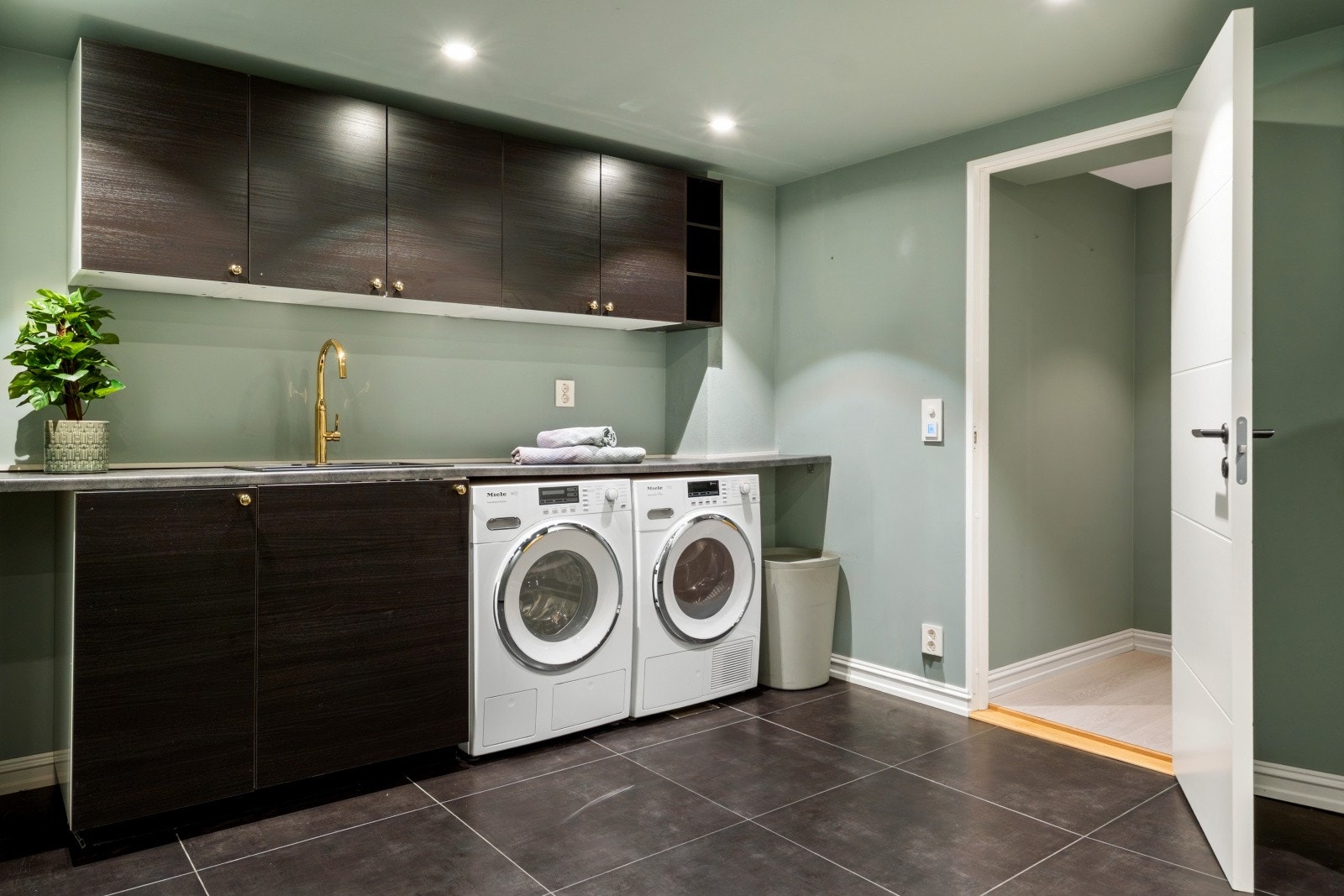 Praktisk og romslig vaskerom med opplegg for vaskemaskin og tørketrommel, utslagsvask og god lagringsplass Galleribilde