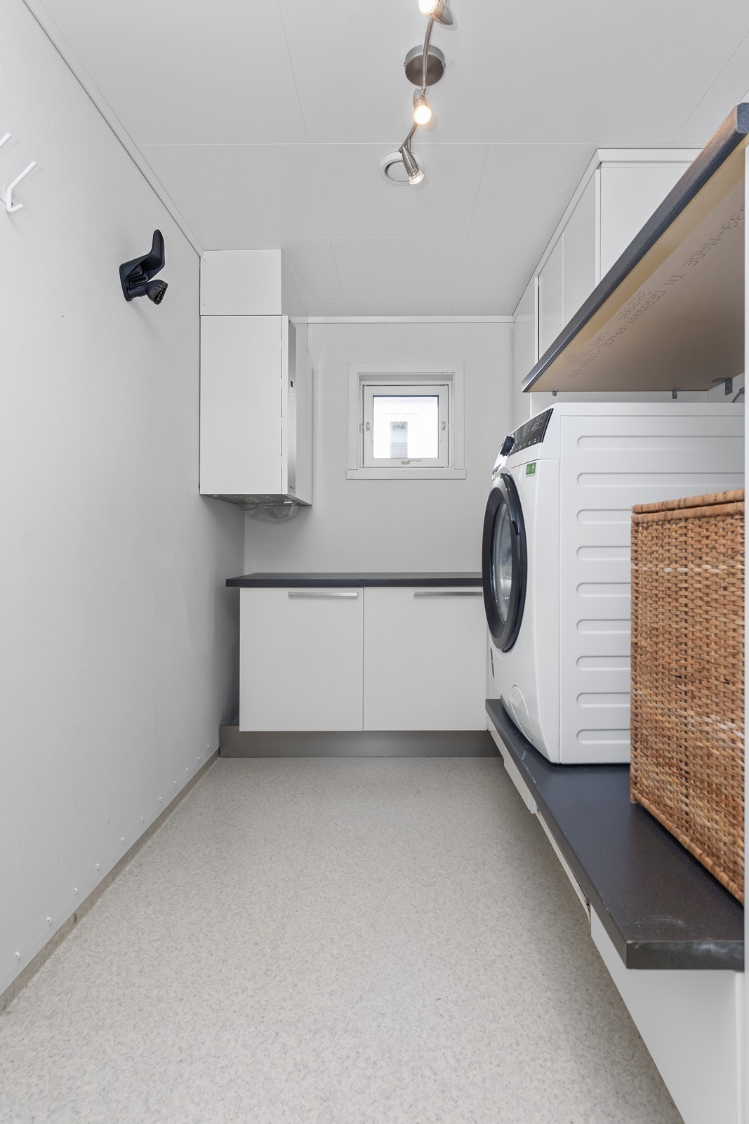 Vaskerom med plass til både vaskemaskin og tørketrommel i høyden, samt god oppbevaringsløsninger Galleribilde